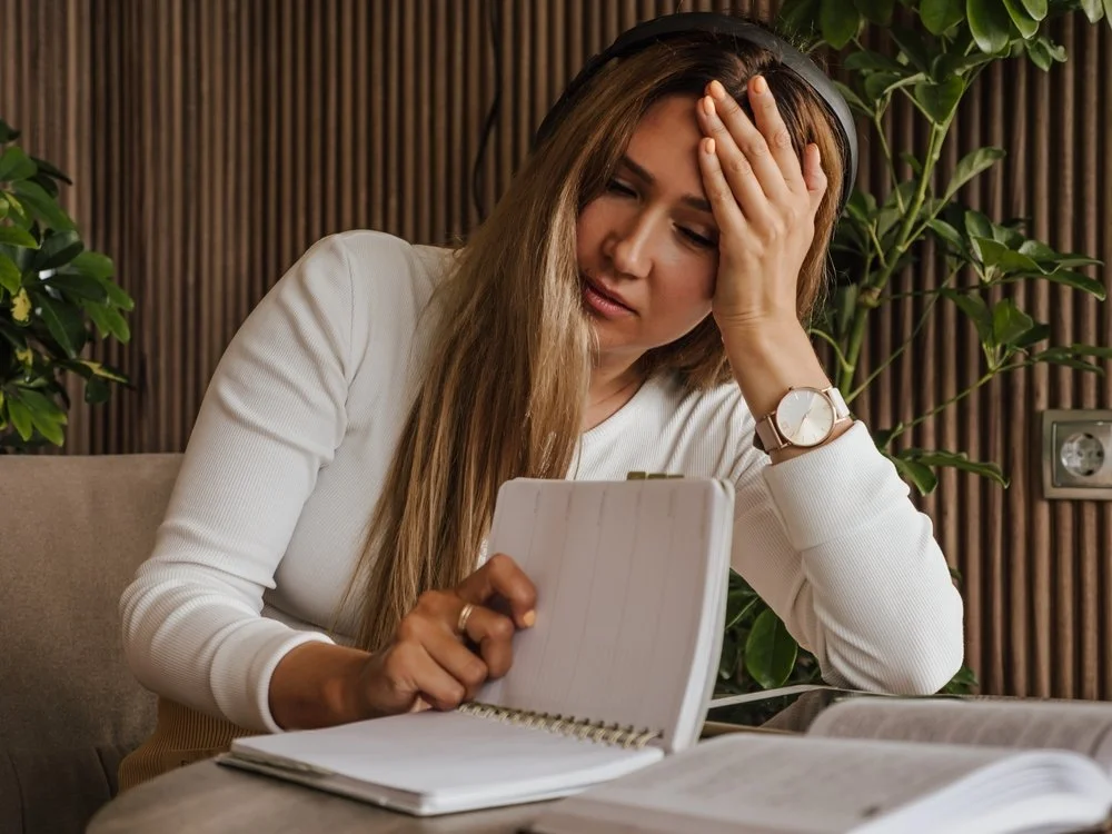Woman struggling with ADHD and dyslexia, holding head in frustration, problems with reading.
