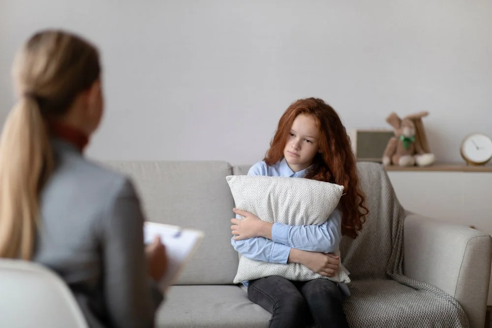 Young girl with red hair holding a pillow in therapy