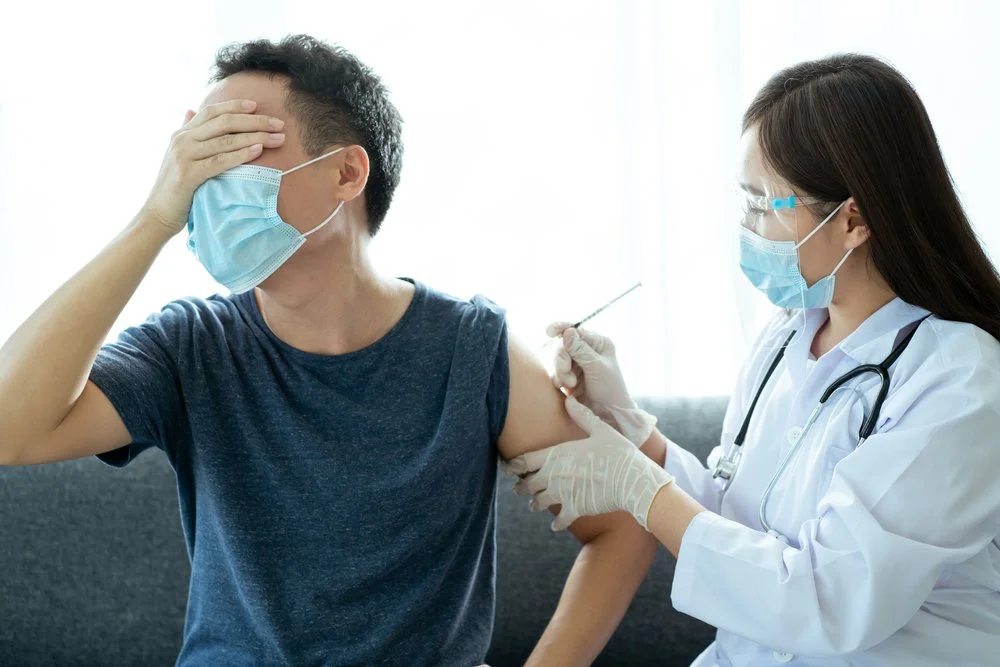 Man with a mas afraid of nurse with needle