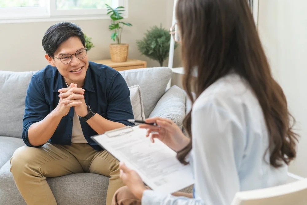 Happy man sitting on couch during therapy session with female therapist