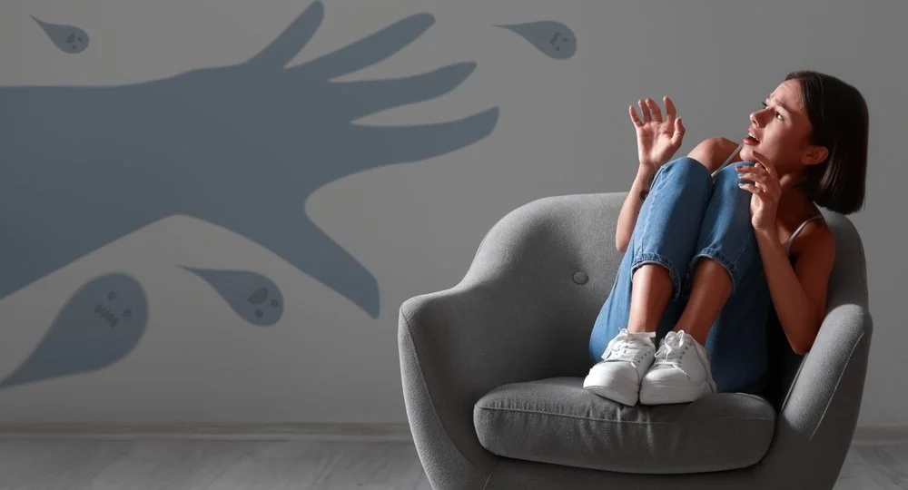 woman scared sitting chair looking at graphic of a hand