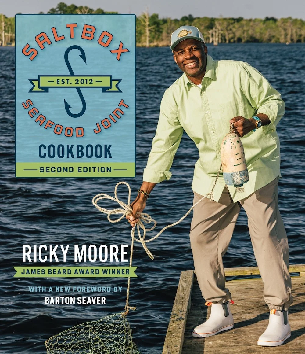 Chef Ricky Moore with a fishing net on the cover of the Saltbox Seafood Joint Cookbook