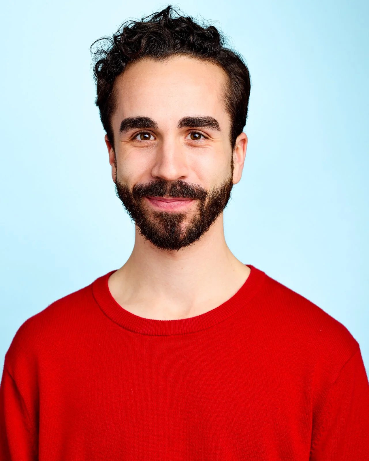 Professional commercial actor headshot of a man in a red sweater, shot in a Toronto studio for casting portfolios.
