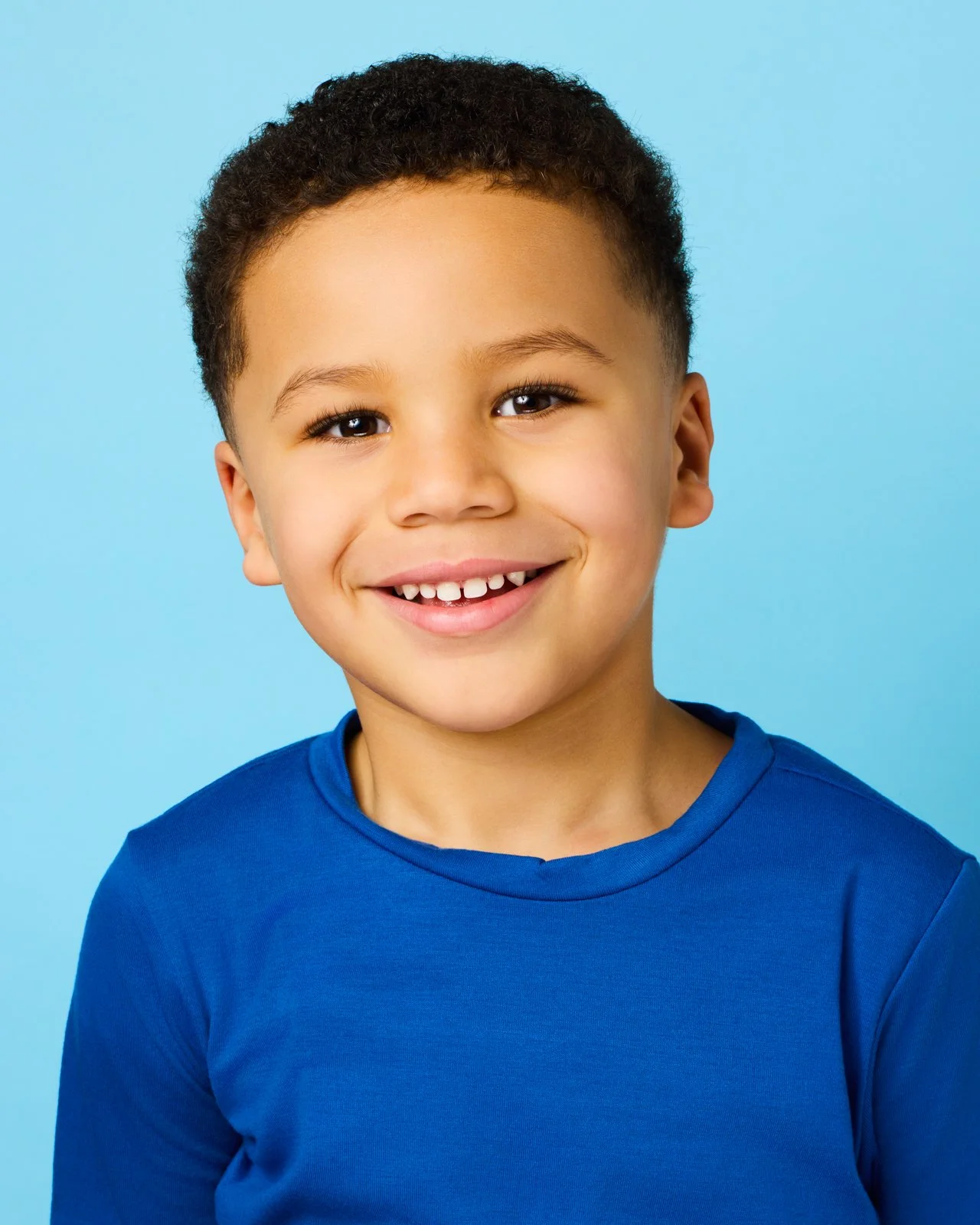 A professional youth actor headshot of a boy in a blue shirt, featuring a natural and engaging expression for casting directors.