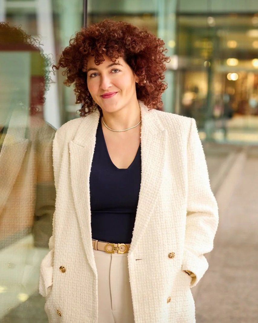 A professional environmental headshot of a woman in a white blazer, showcasing a modern corporate style for Toronto teams.