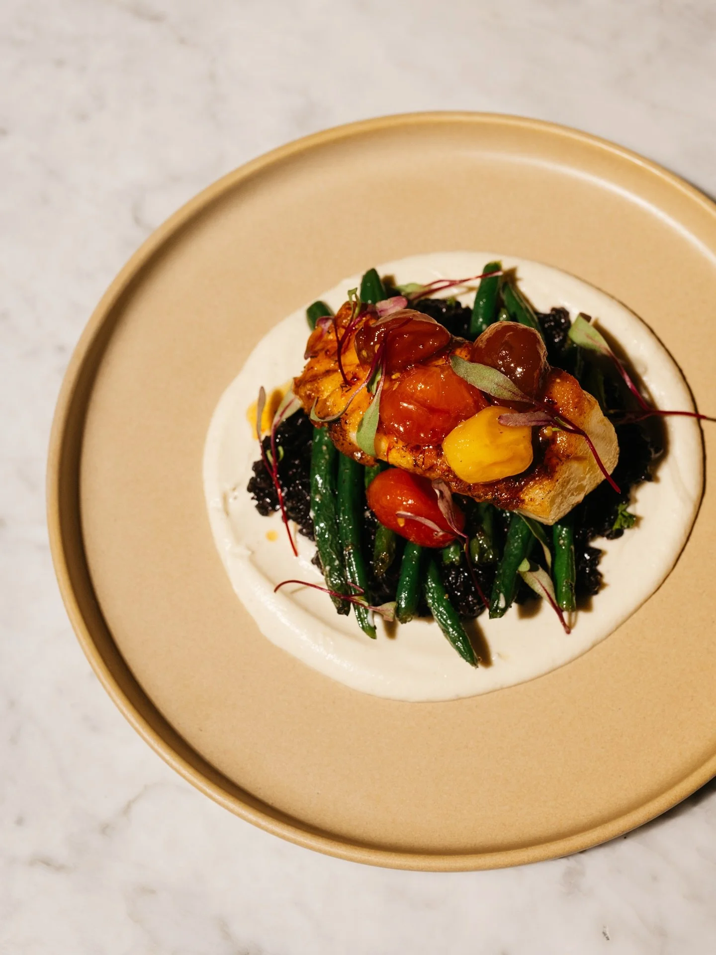 Pan-seared sea bass over creamy parsnip purée, black rice, and haricot vert topped with tomato jam and a touch of saffron butter.✨ 
Now on the fall menu reserve your table at the link in bio. 🍽️