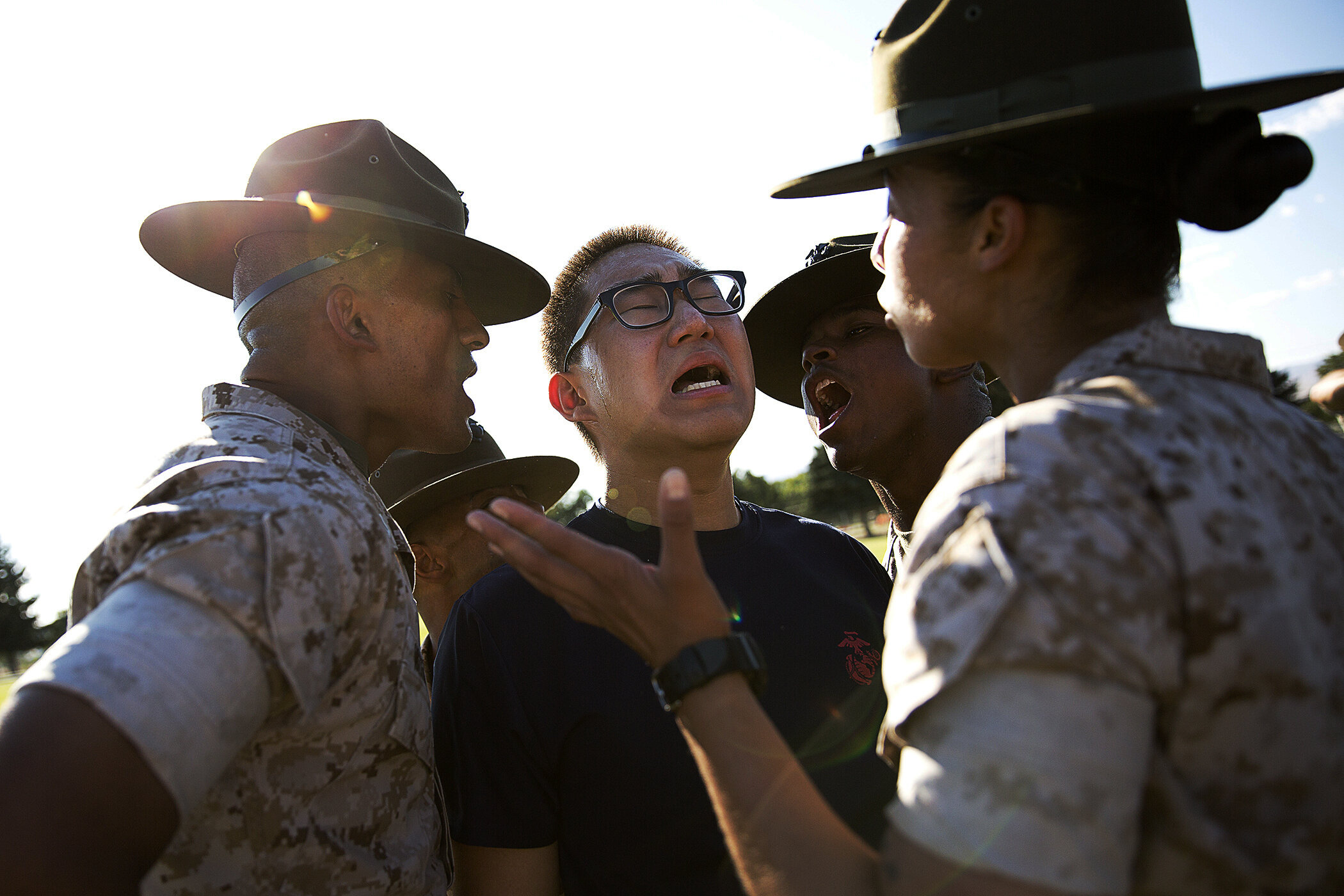 Marine Corps drill instructors provide guidance to a recruit at boot camp.