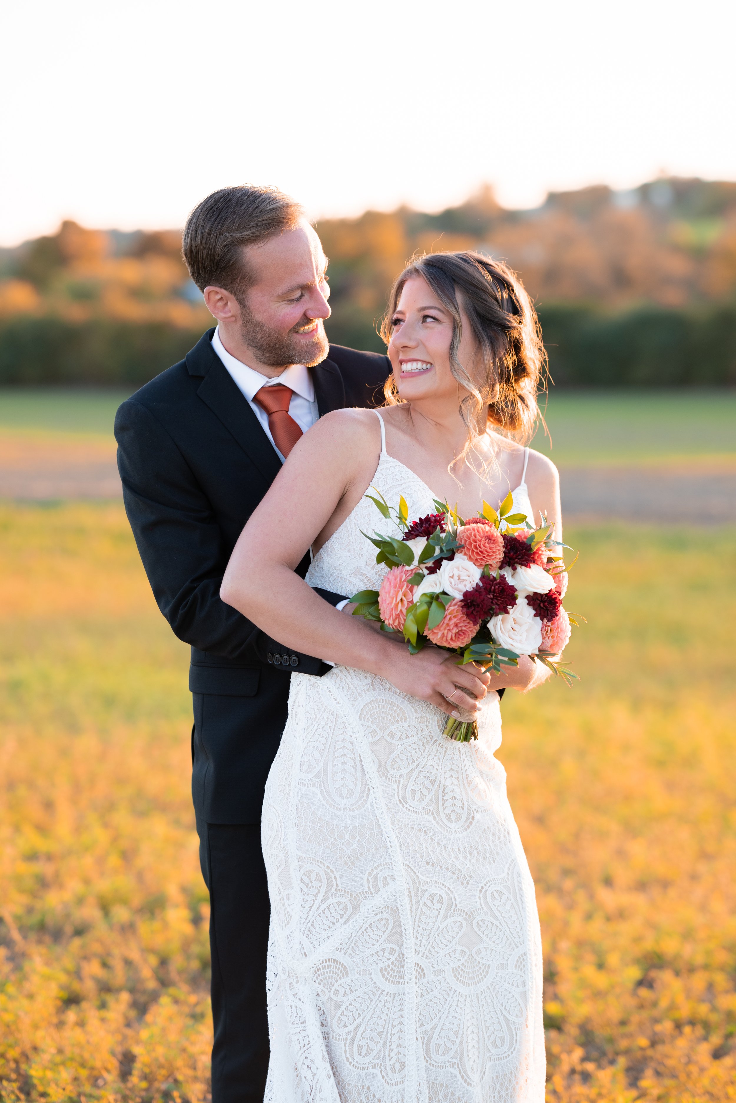 Bride and groom smiling at each other during golden hour at Rolling Grape Vineyard in Bailieboro, Ontario