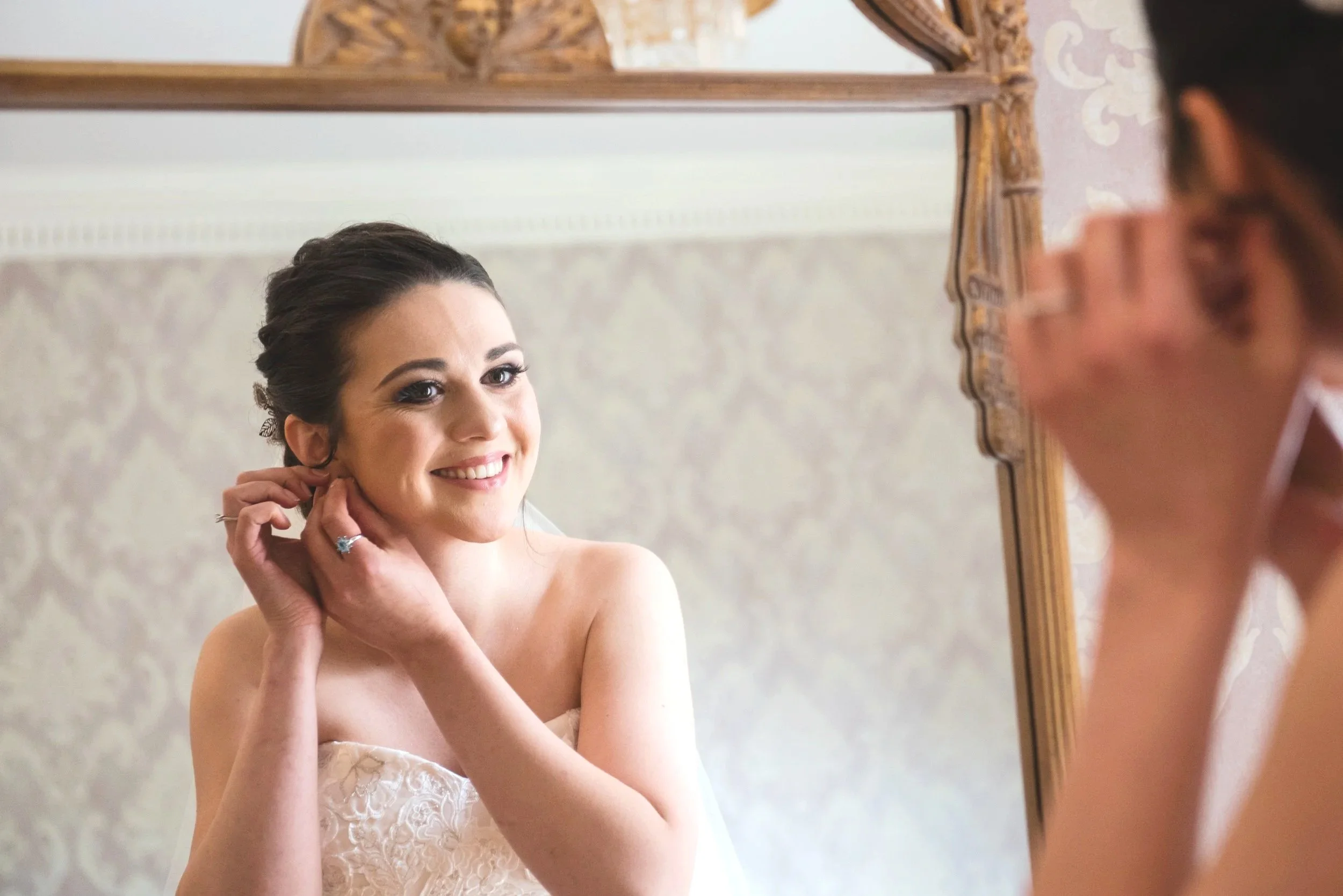 Bride putting on her earrings while getting ready at McLean House Estate in Ontario.