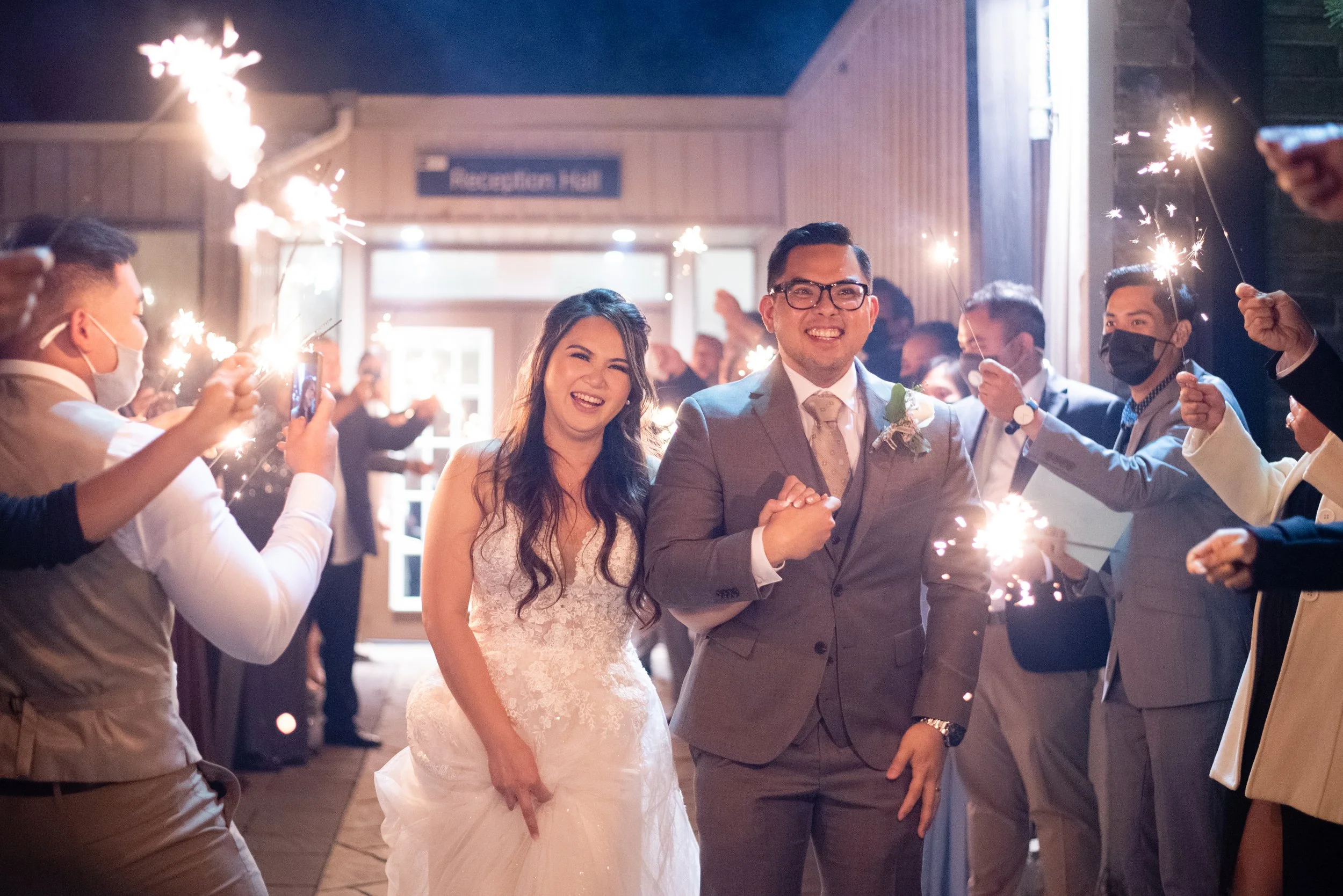 Bride and groom laughing as they walk through a sparkler exit at Kedron Dells in Oshawa, Ontario.
