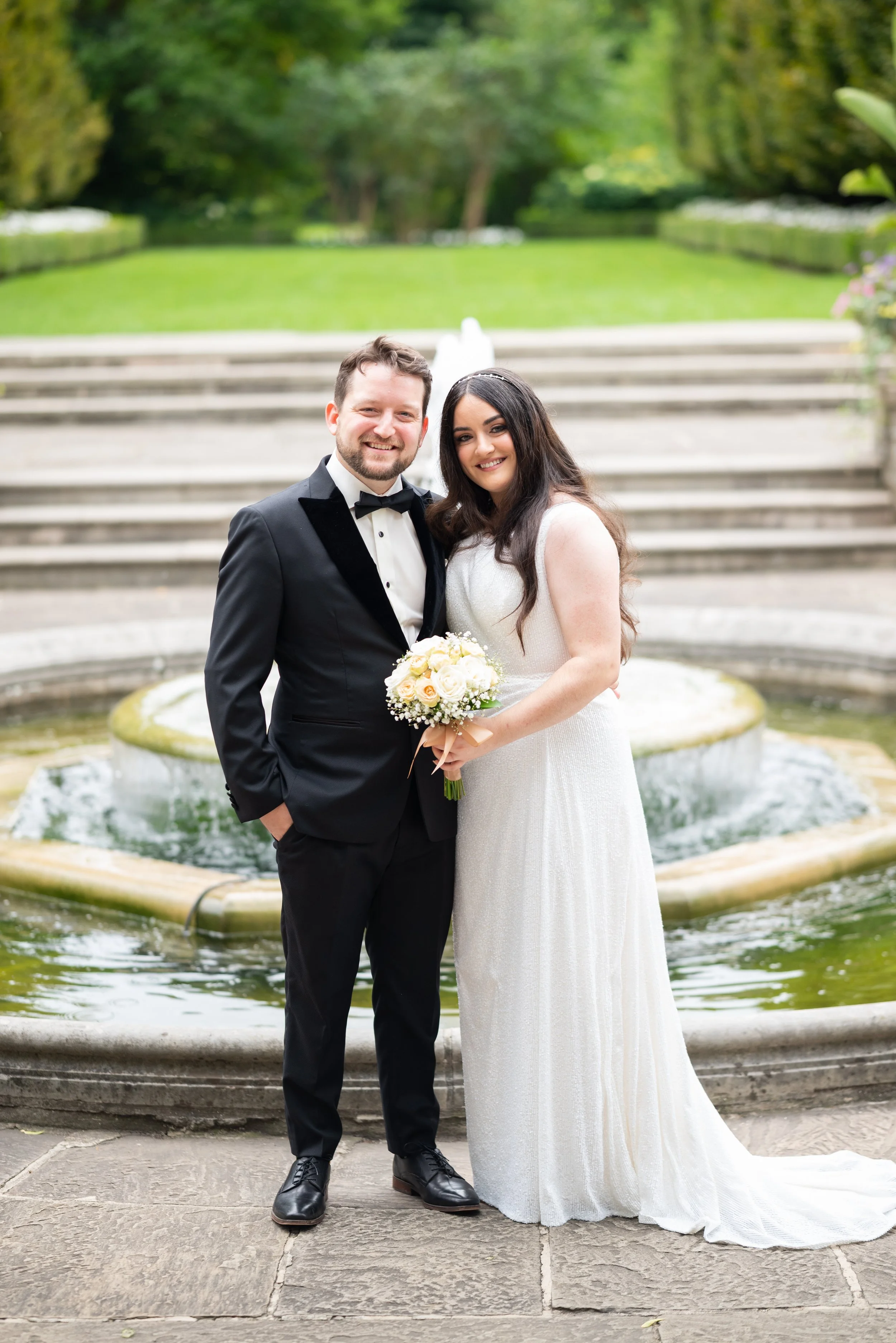Bride and groom posing by the fountain at Graydon Hall Manor in Toronto, Ontario