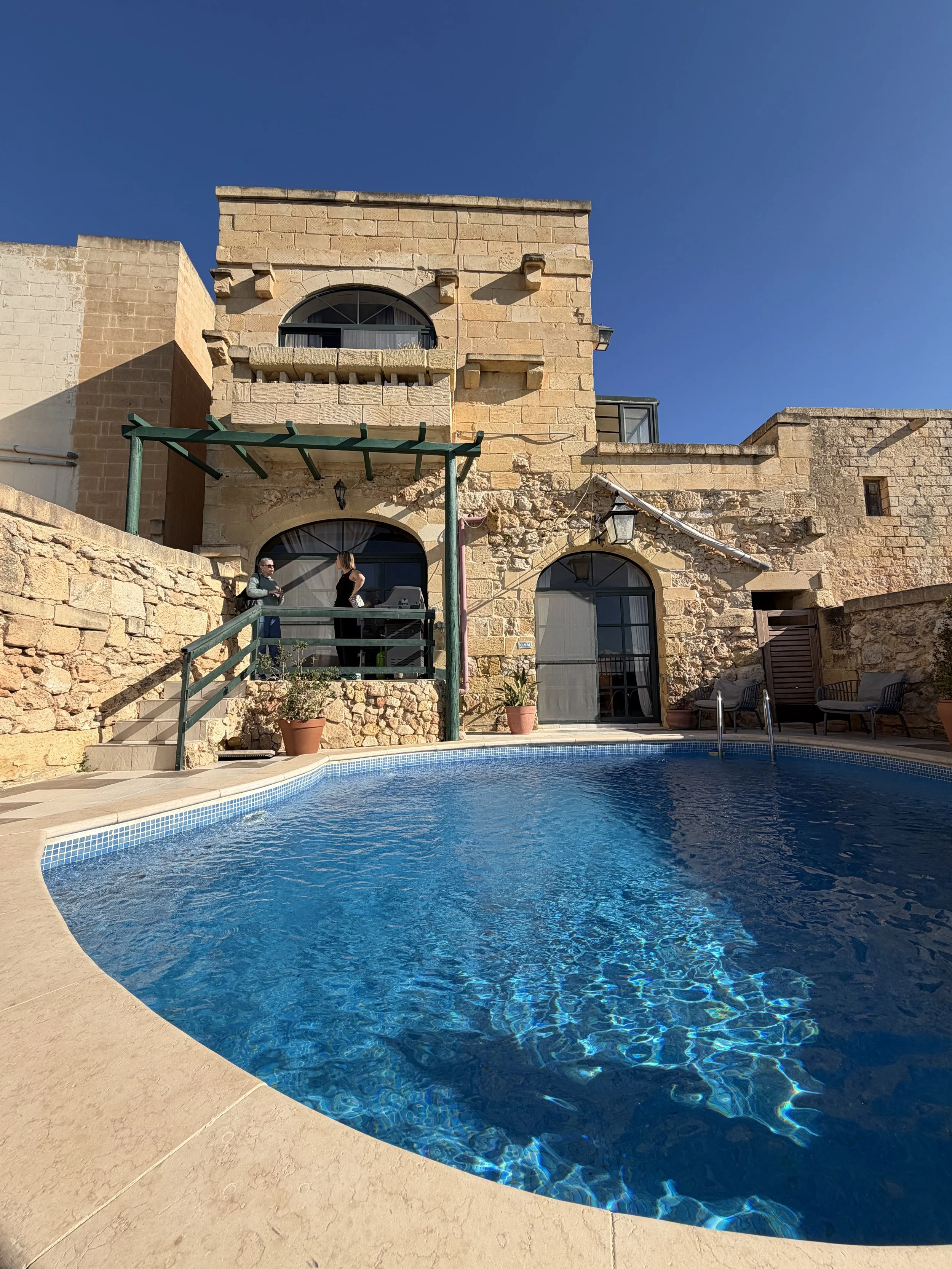 Mediterranean sand coloured building with blue swimming pool.