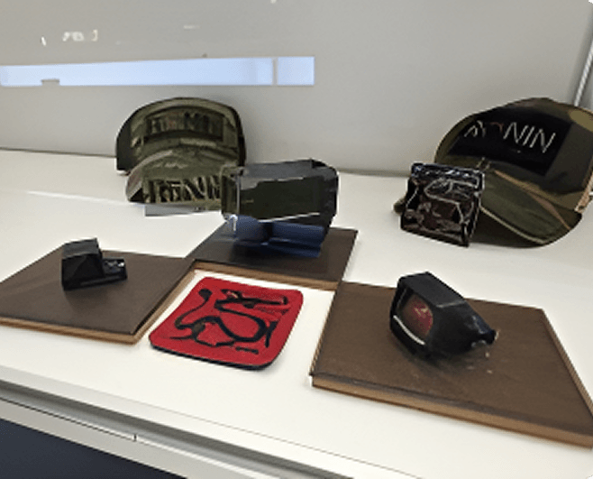 Display with several handbags, a red textile art piece, and a few small items on wooden stands.