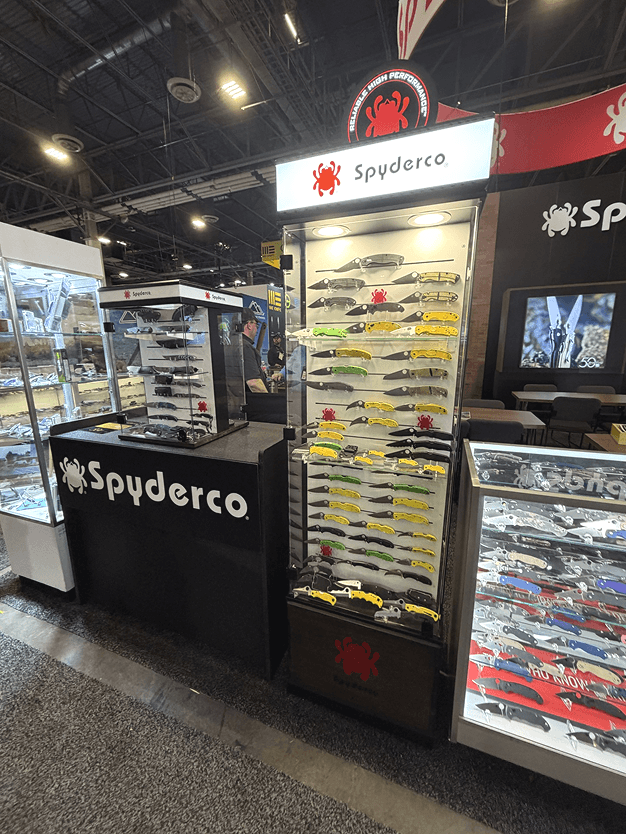 Display of Spyderco knives and collectible toy cars at a trade show or store, with Spyderco branding visible.