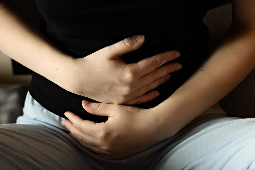Woman gripping stomach - When You Finally Get Pregnant After Infertility… and Feel Anxious Instead of Happy