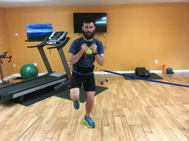 Side to Side Single Leg Hop using sports cord or cable - hop from one leg, to the side, landing on the other leg CLOSEST TO THE CABLE (holding weight for core challenge)