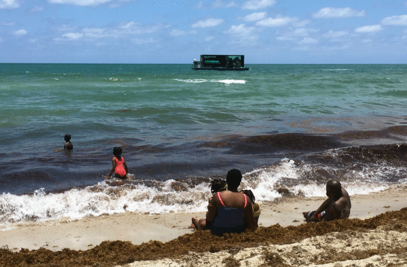 Beach goers look at the LCD screen showcasing historical images of the black community partaking in different festivities in Miami Beach. Photo by Terrisa Mark / WLRN News