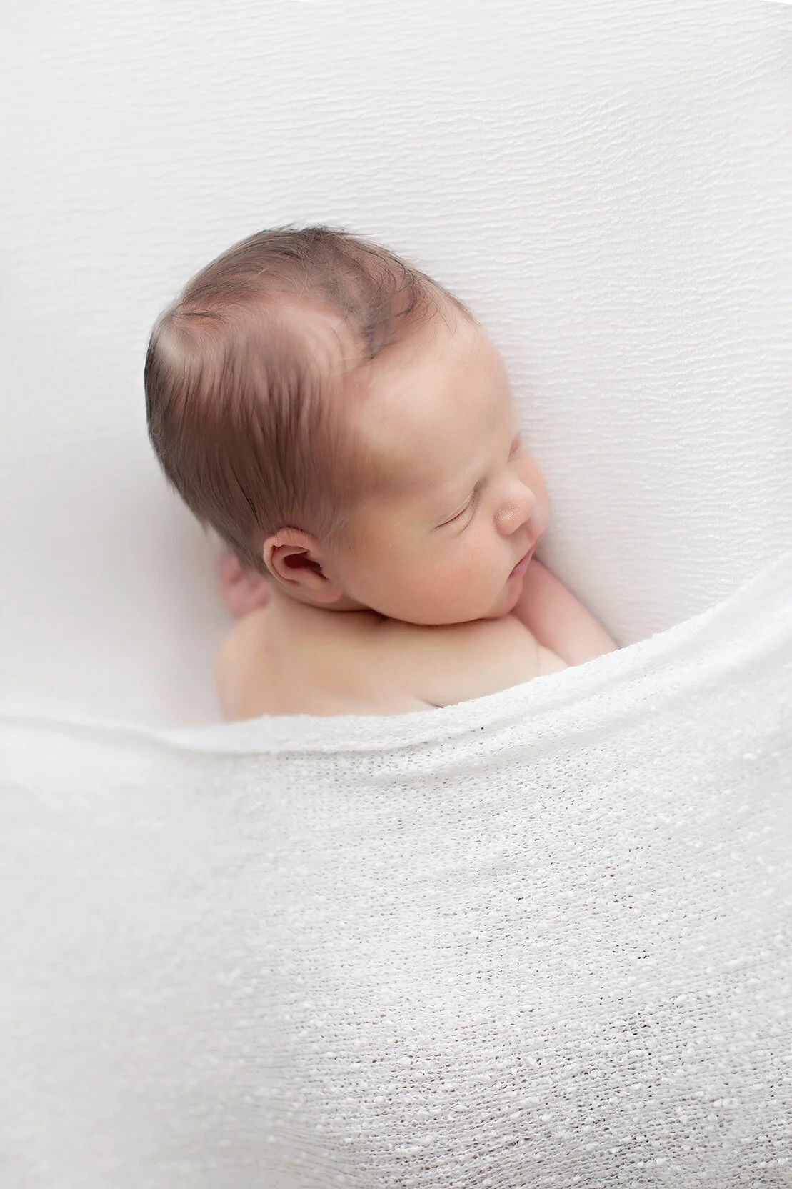 Newborn sleeping on white blanket