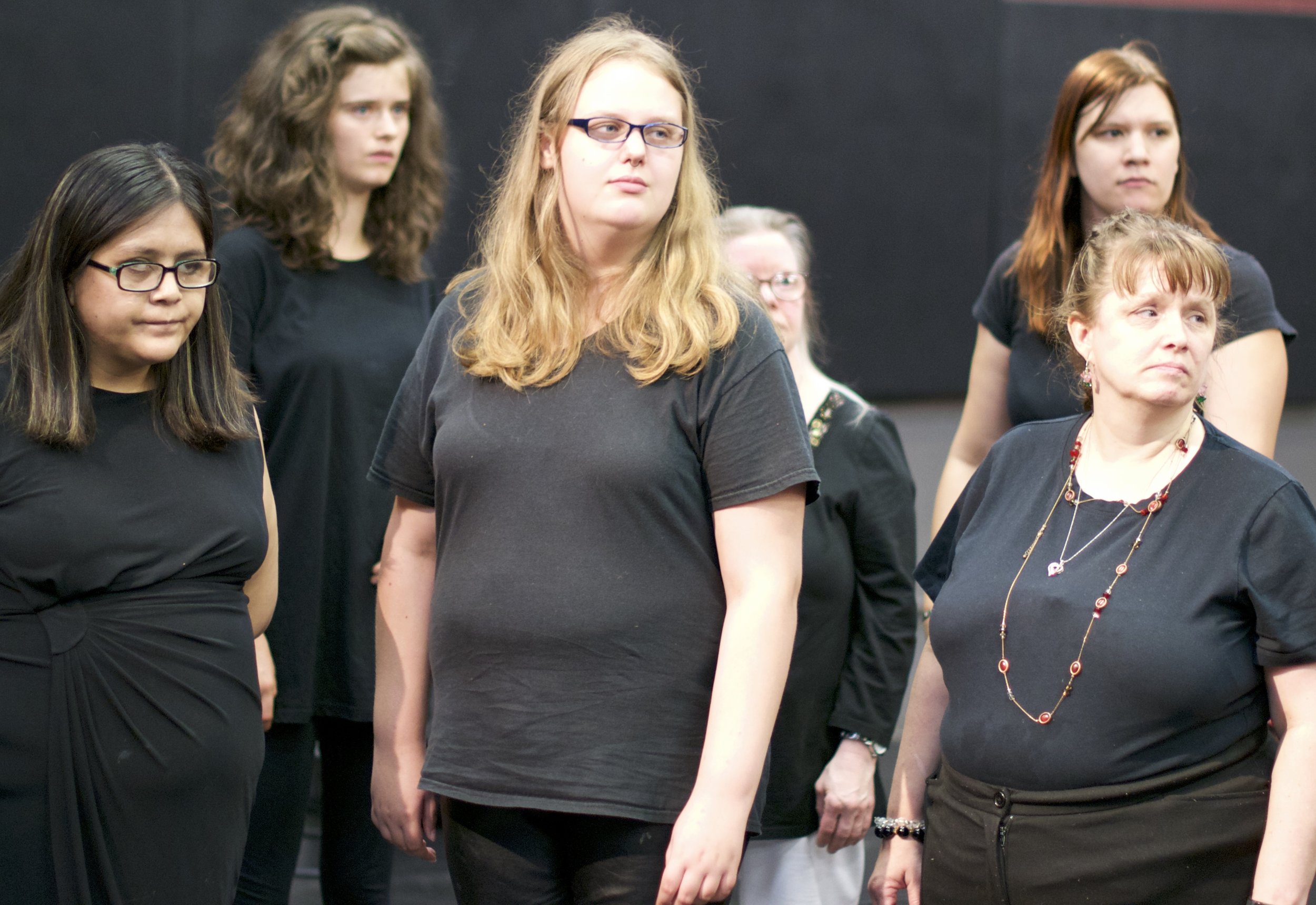 Group of women dressed in black look off to the side