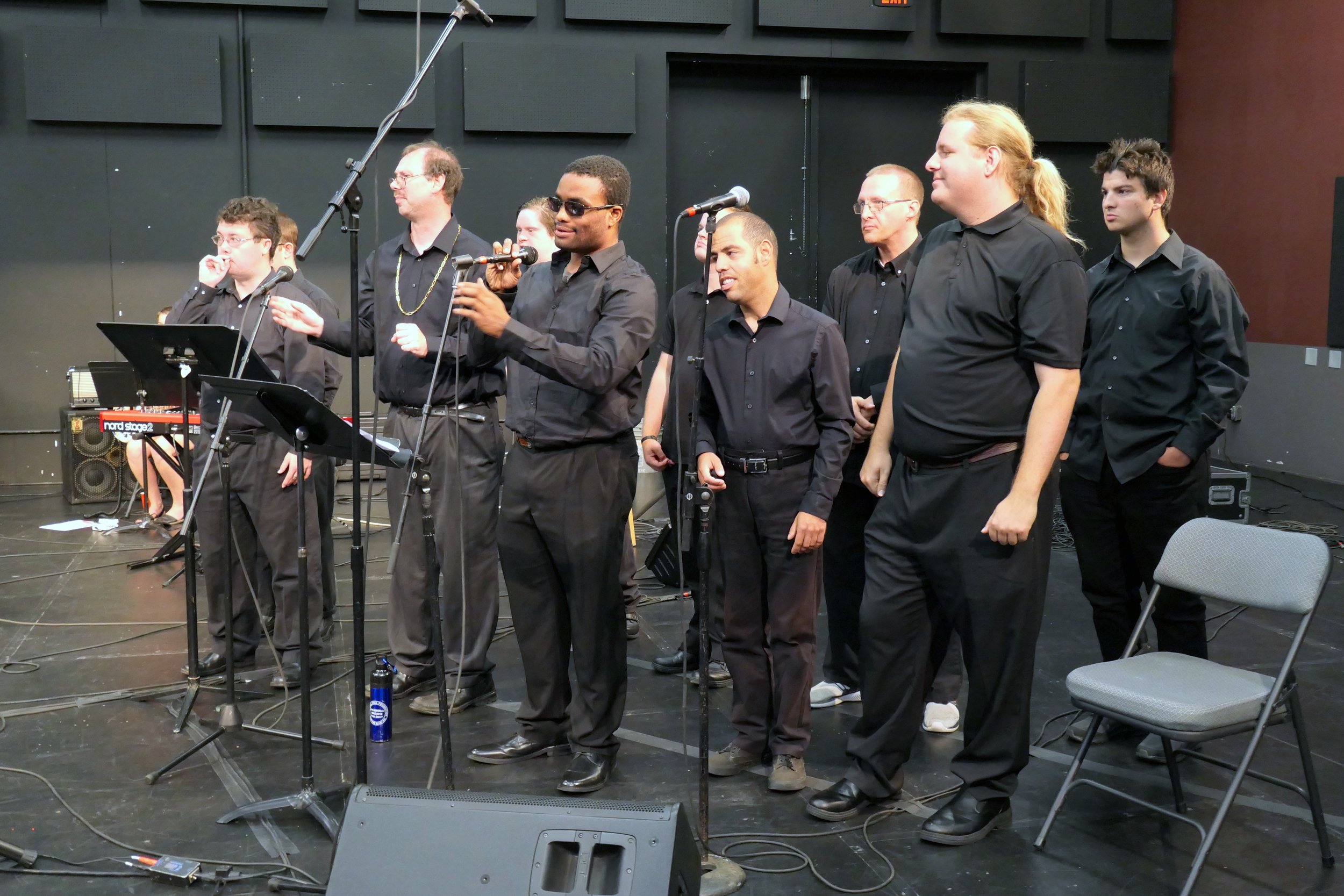 Group of men standing in a theatre in front of sound equipment