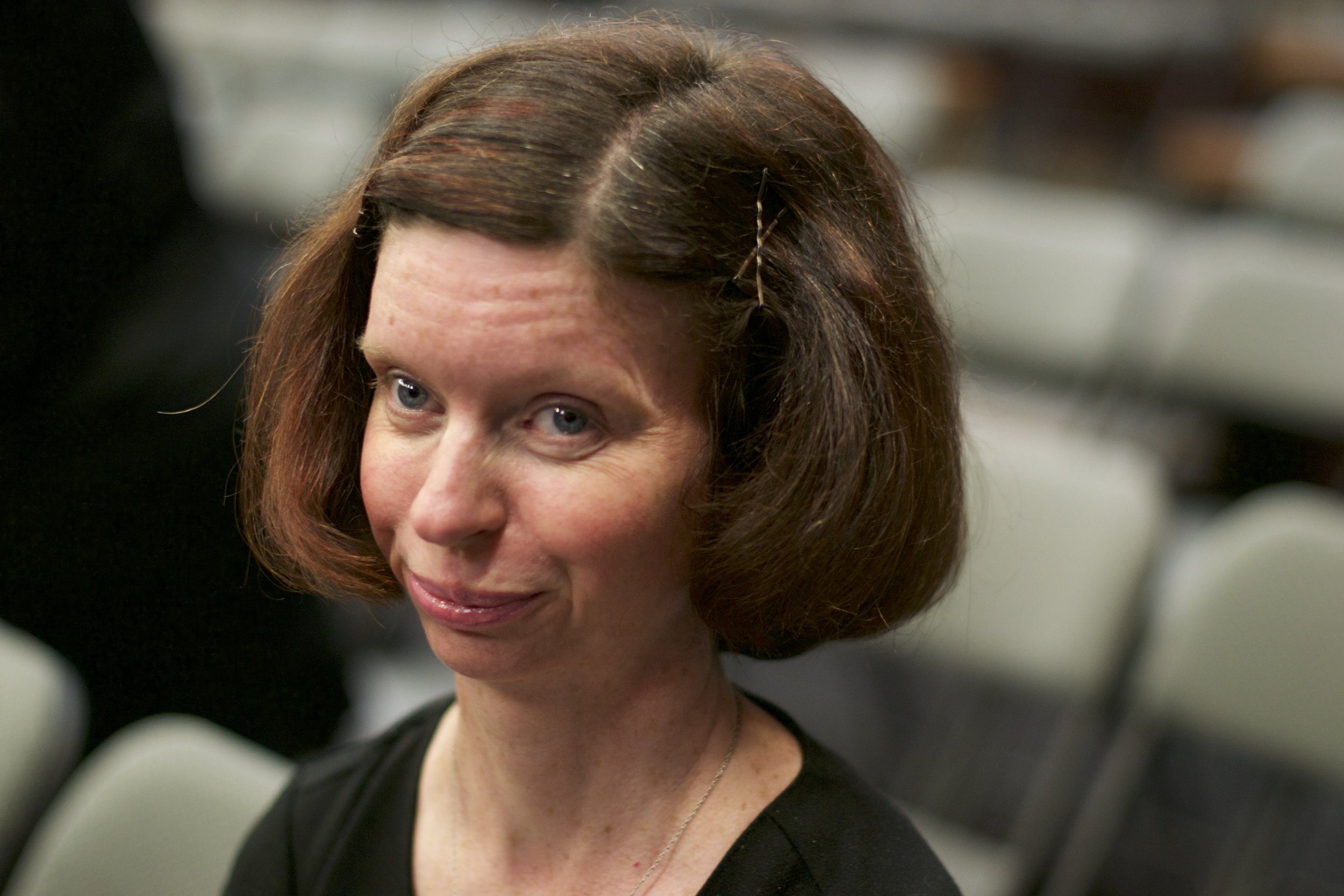 Close up of young woman's face, she has short red hair and smiles