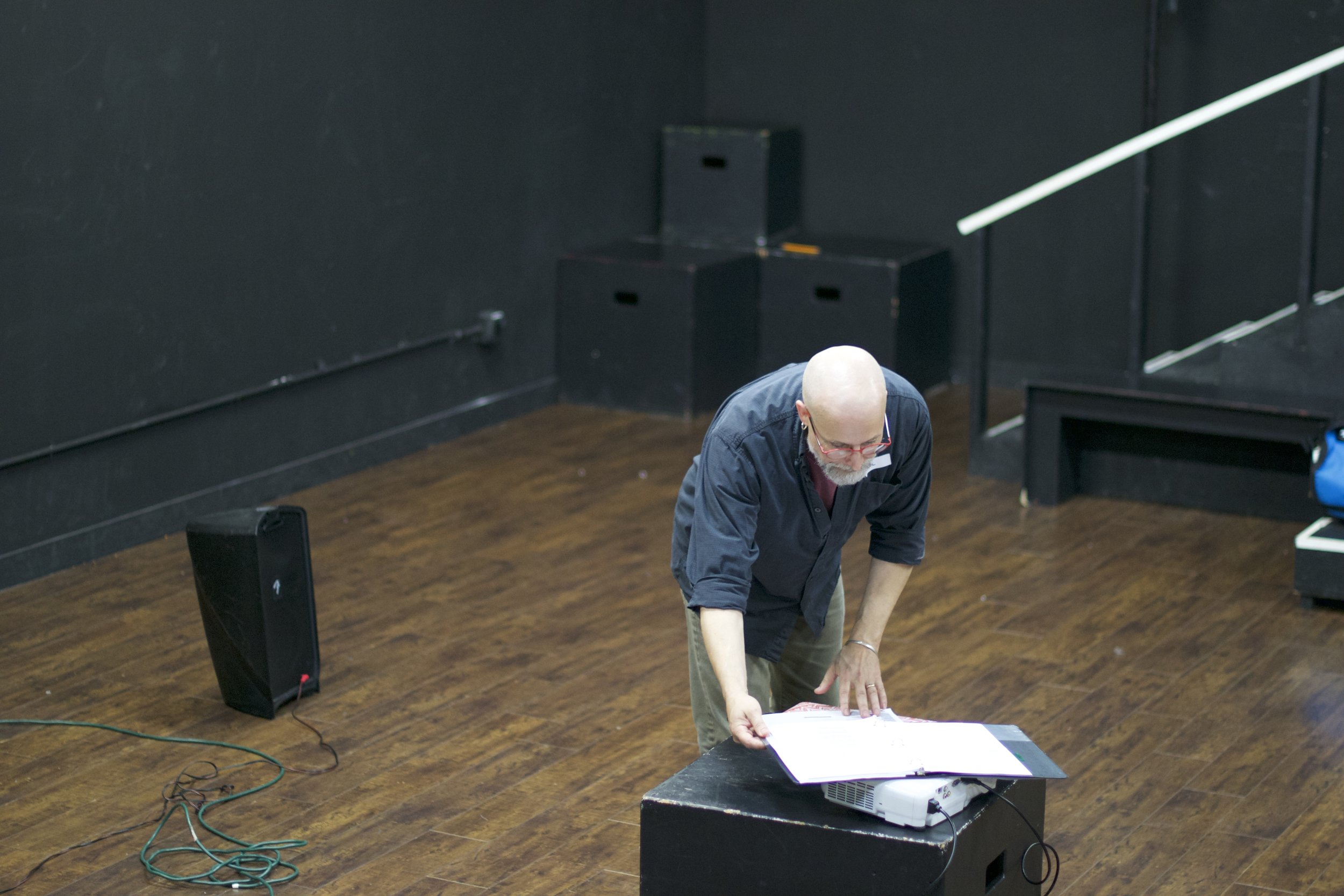 Man bending over in a black box theatre 