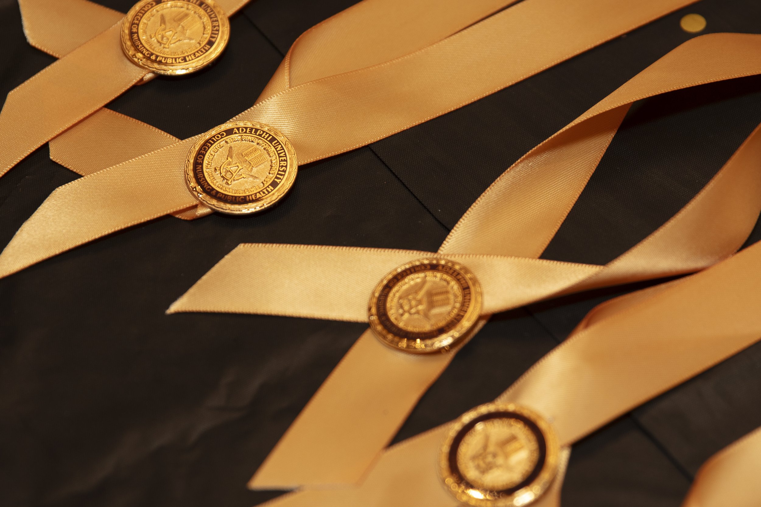 Medals with gold-colored seals and matching golden ribbons laid on a black surface.