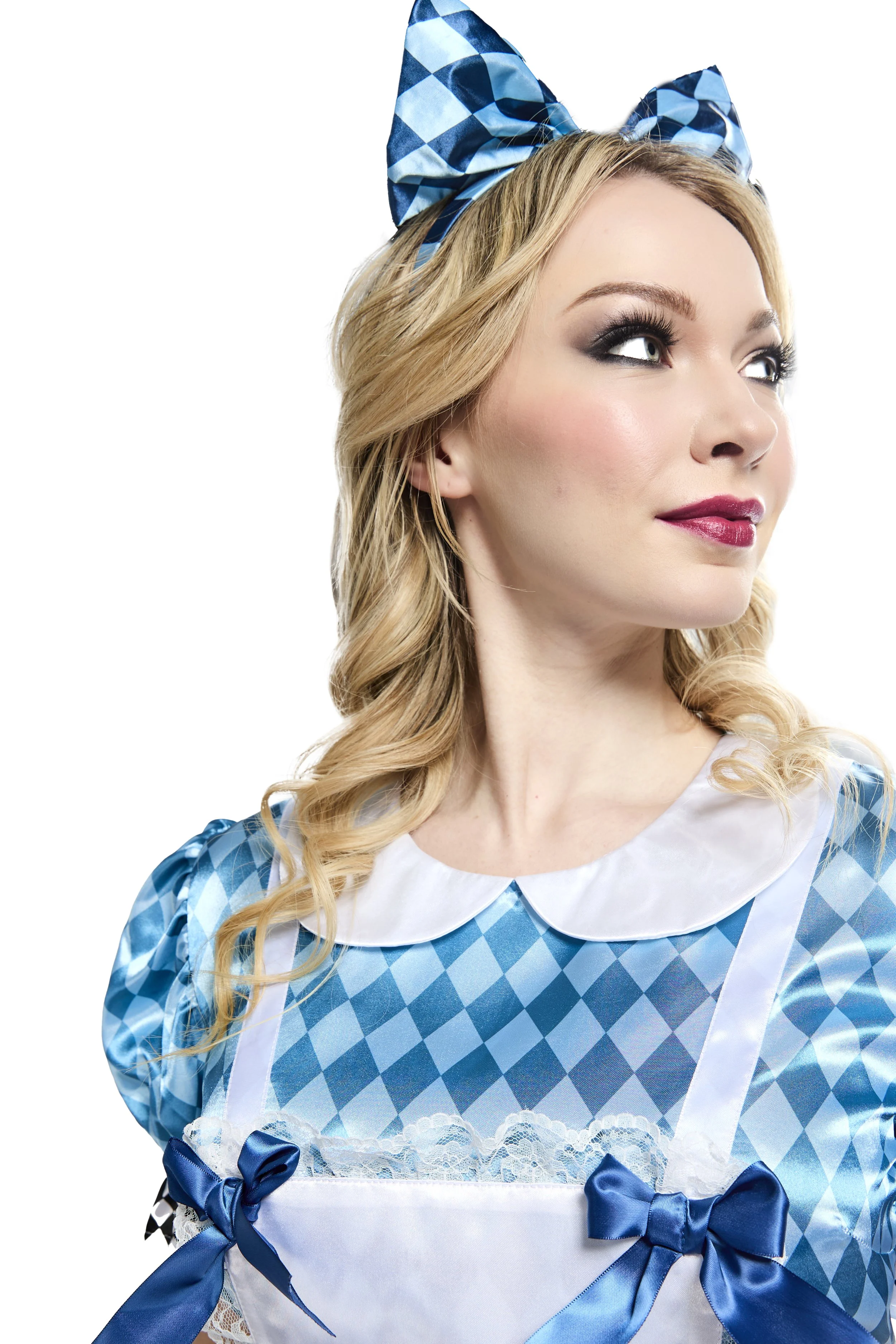 A woman with blonde, curly hair wearing a blue and white gingham dress with a white collar and apron with blue bows and lace. She has makeup with dark eye shadow and lipstick, and wears a large matching blue and white checkered bow on her head, looki