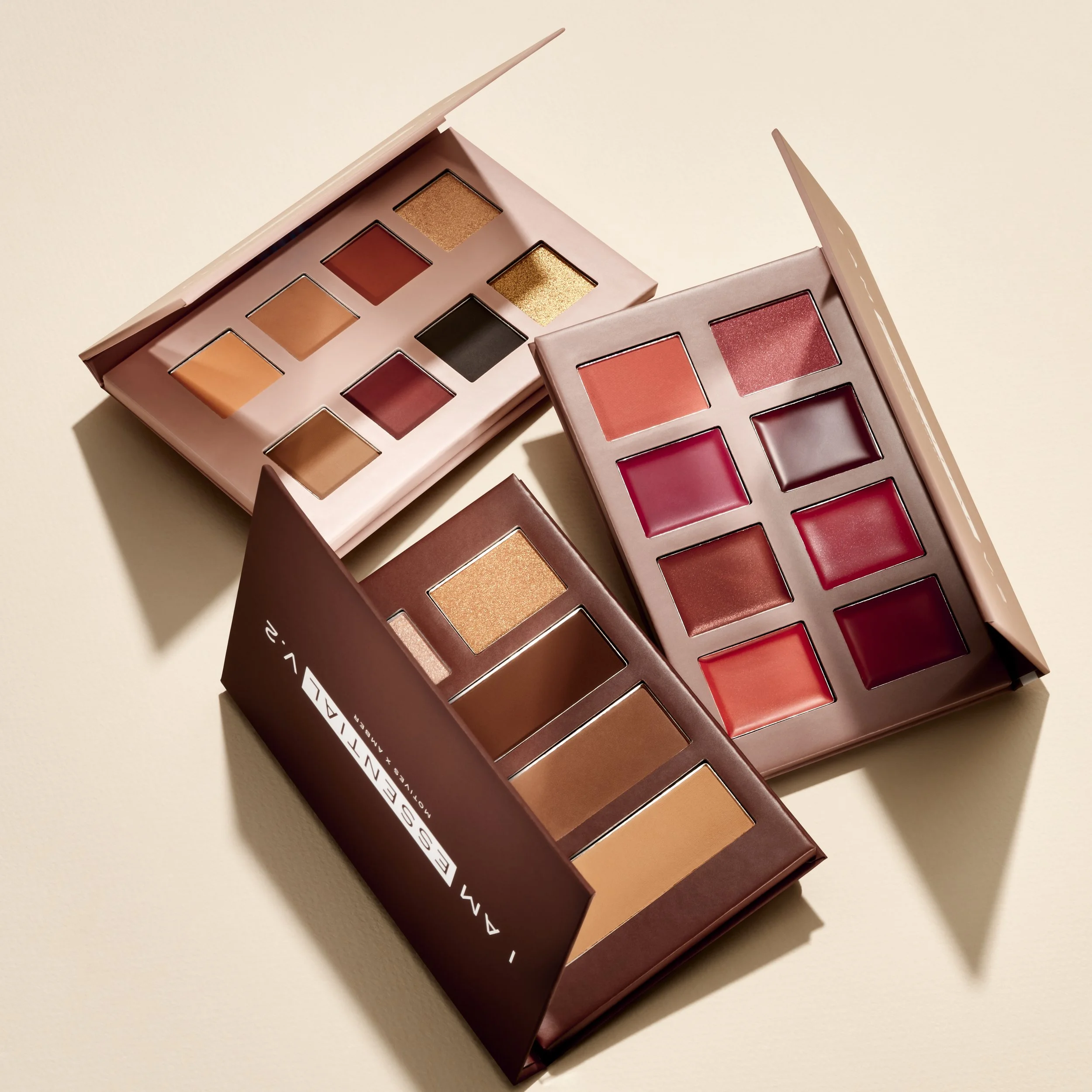 Three open eyeshadow palettes with various shades of brown, red, and gold.