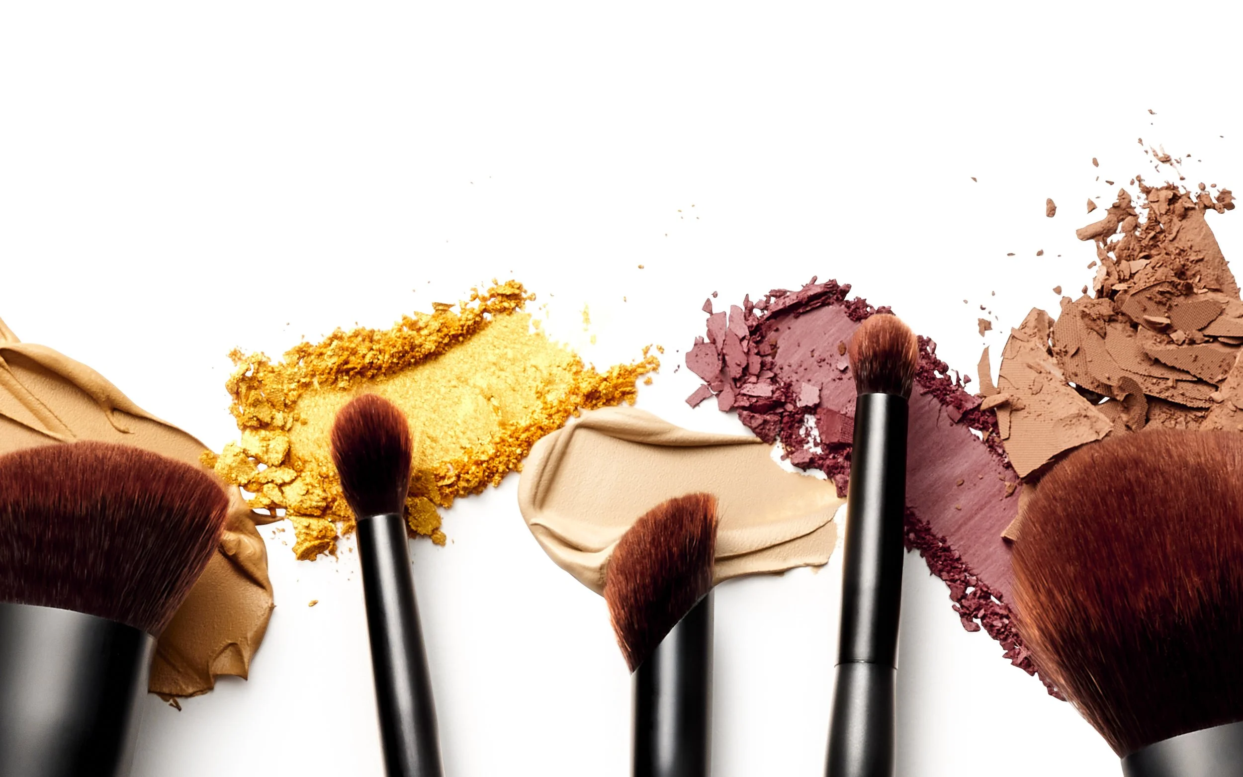 Four makeup brushes with different colored powders and creams on a white background.
