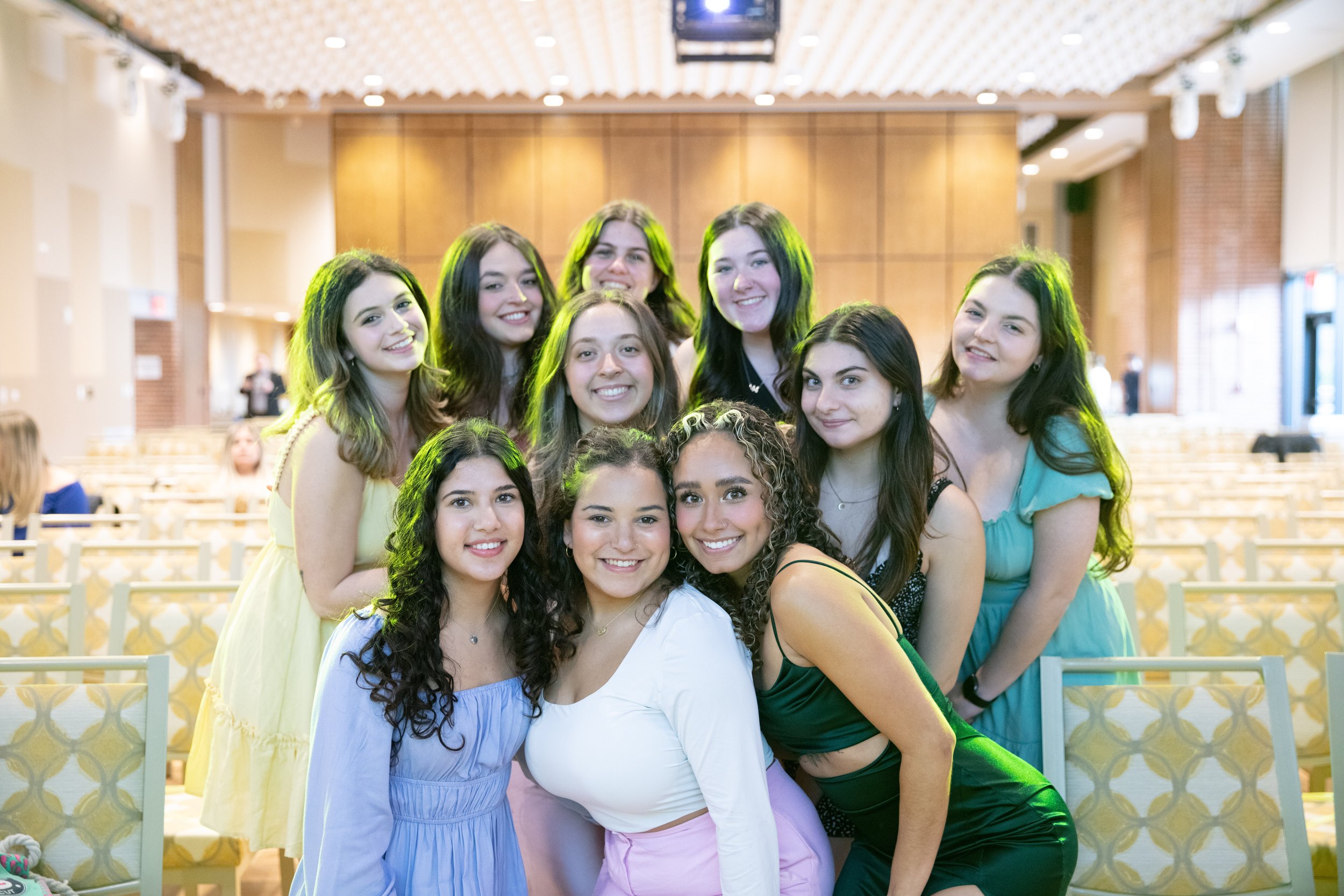 A group of ten teenage girls smiling and posing together indoors at an event or gathering.