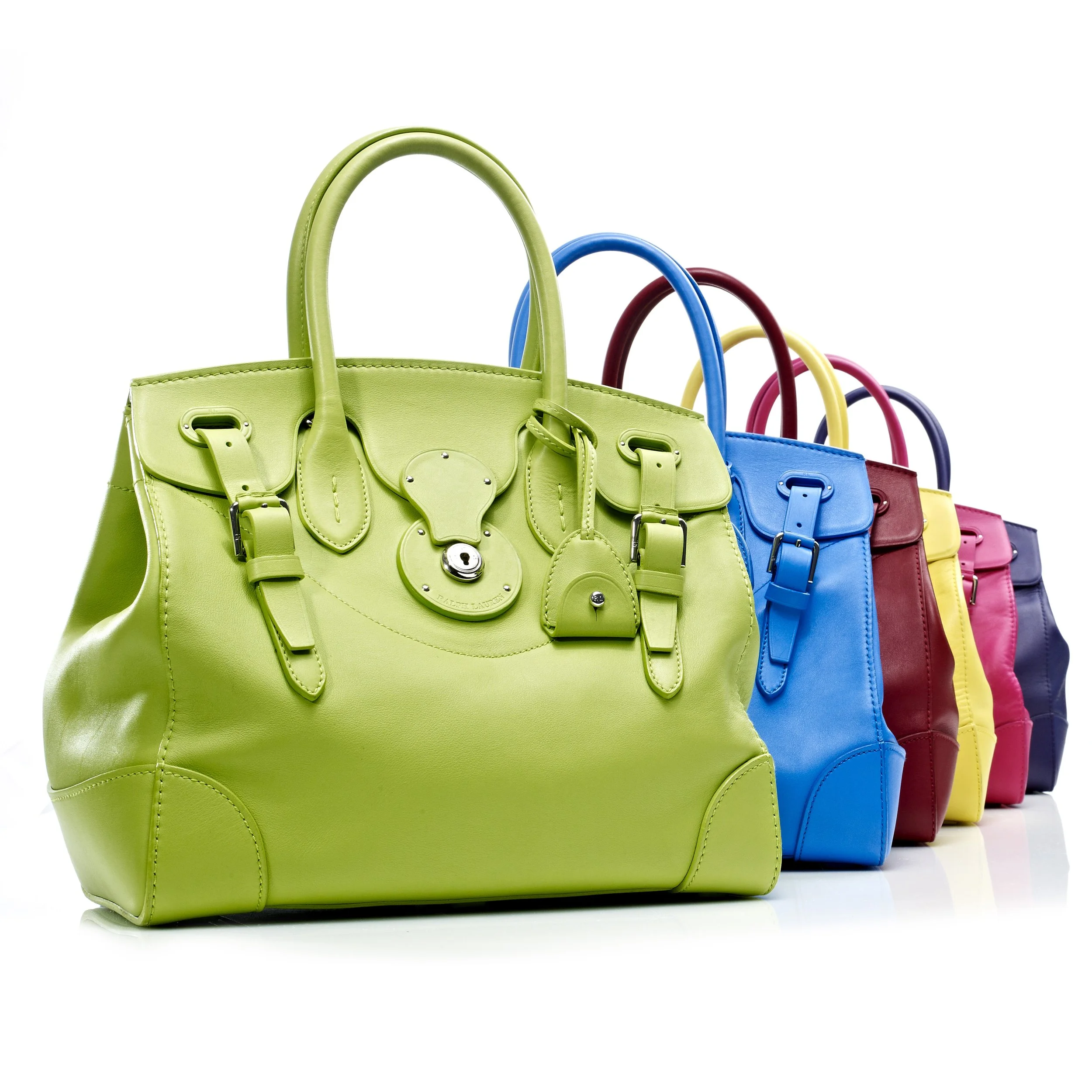 Colorful handbags in green, blue, red, yellow, pink, and purple arranged in a row on a white background.