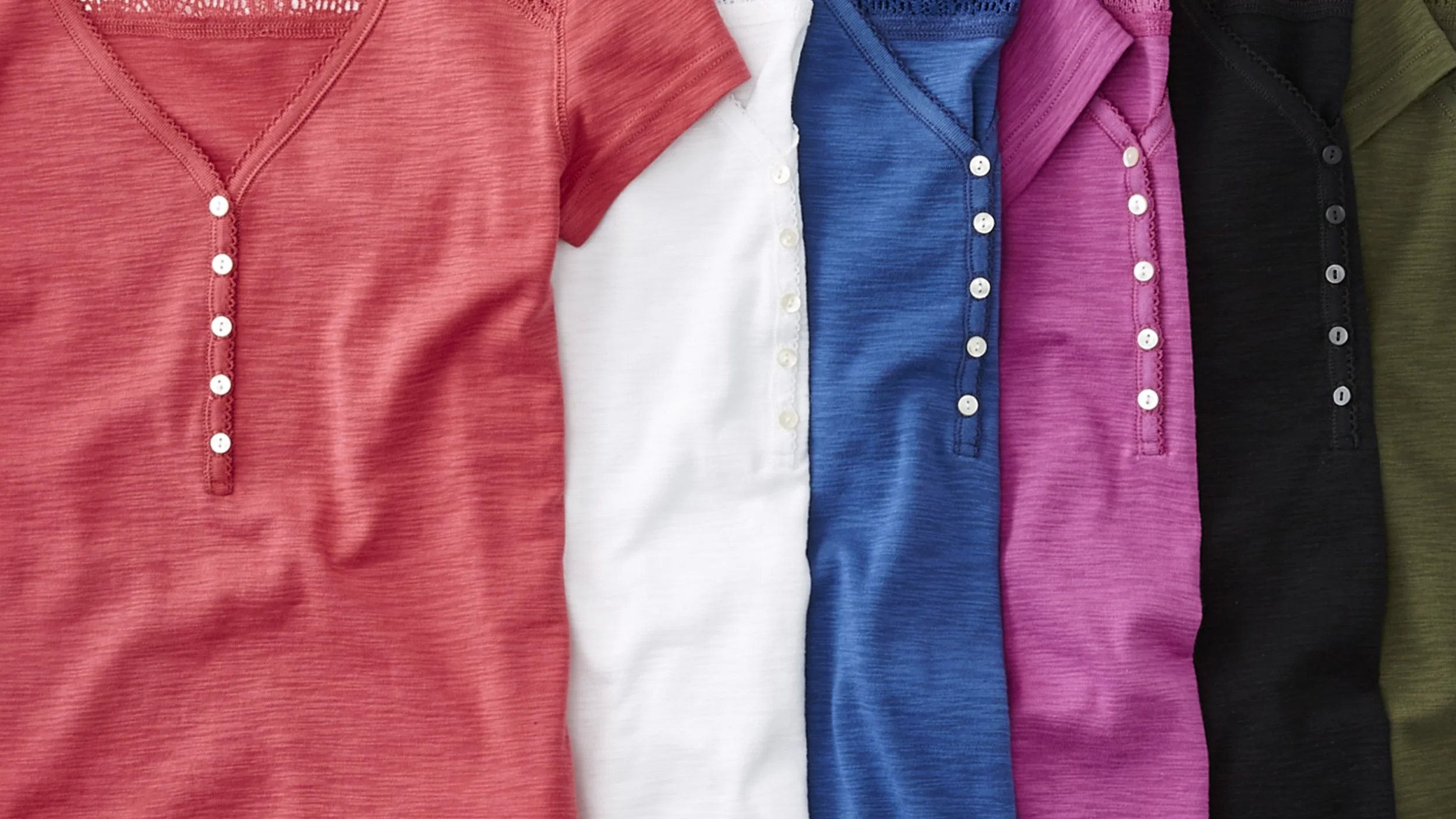 A row of colorful short-sleeve shirts arranged side by side, each with a button placket, in red, white, blue, pink, black, and olive green colors.