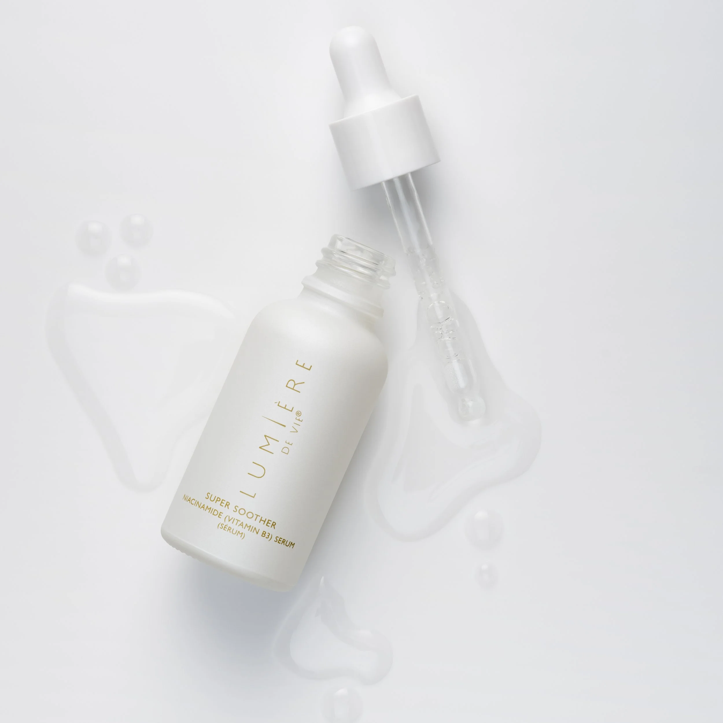 A white skincare serum bottle labeled 'LUMIÈRE de VIE Super S Silher Niacinamide (Vitamin B3) Serum' with a dropper cap, and serum spilled around it on a white background.