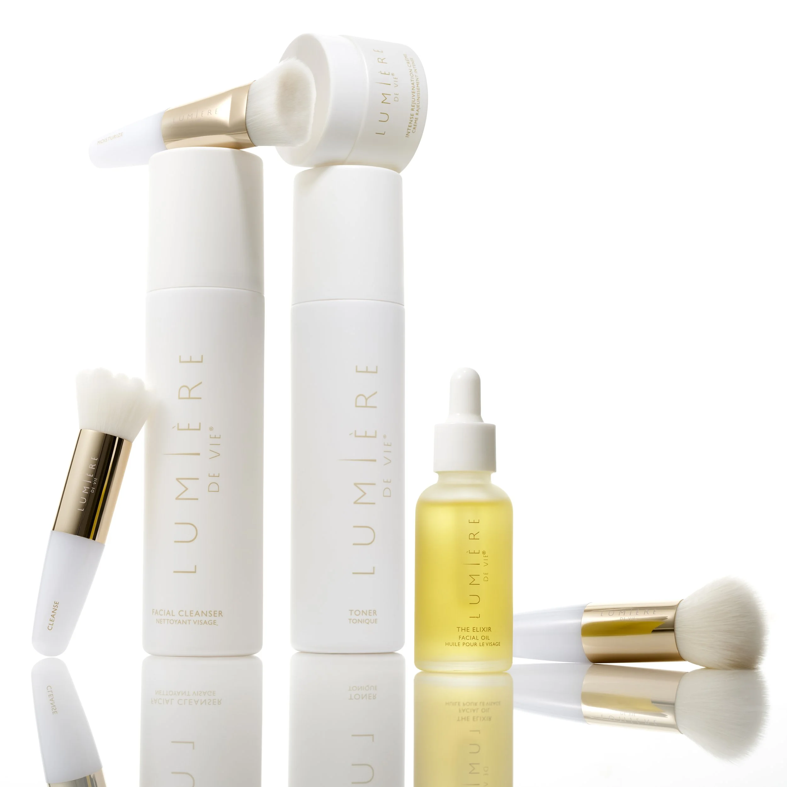 Collection of skincare products and brushes from Lumierre De Vie, including a facial cleanser, toner, facial elixir, and two makeup brushes.