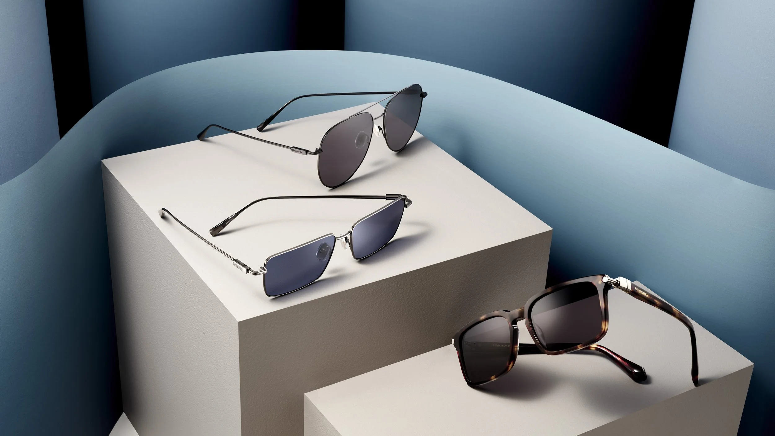 Three pairs of sunglasses on geometric display stands with blue, white, and gray backgrounds.