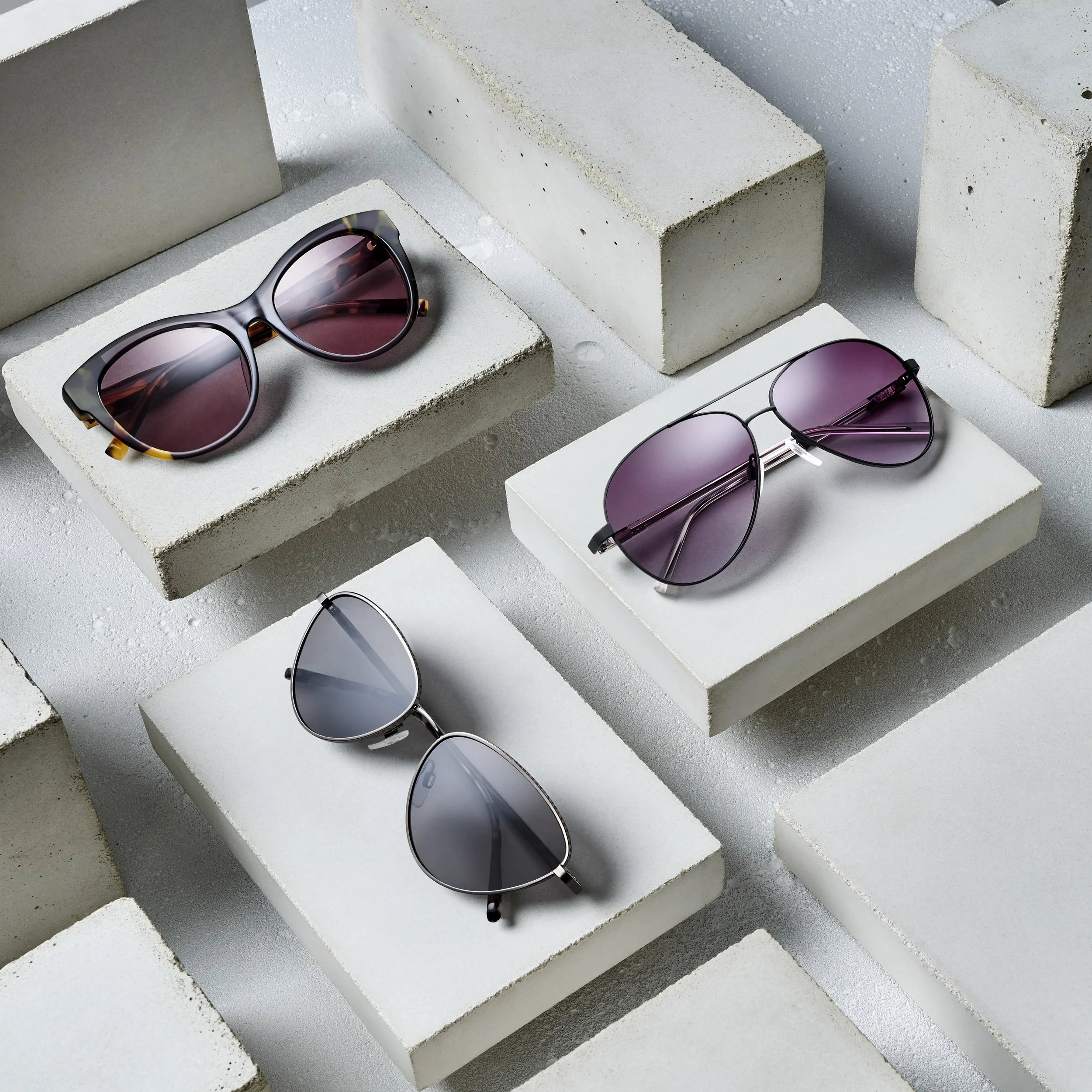 Three pairs of sunglasses placed on white and gray concrete blocks, against a white background.