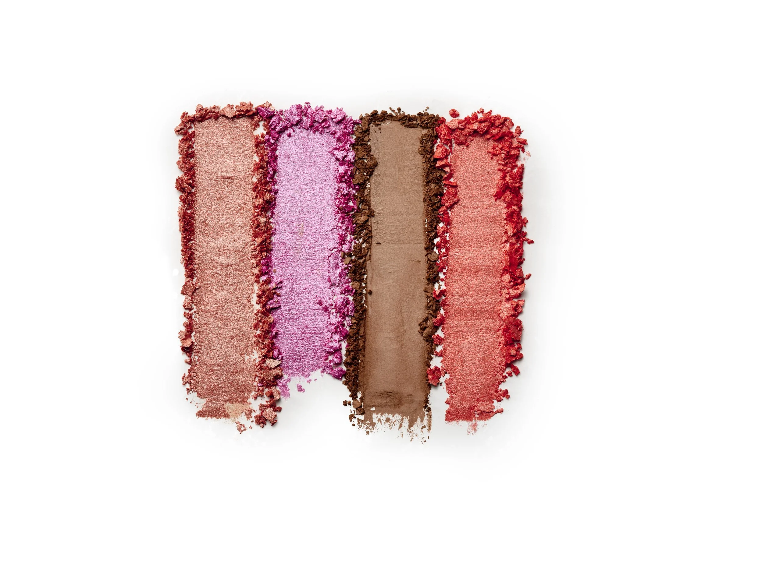 Four swatches of crushed eyeshadow in shades of pink, purple, brown, and red on a white background.