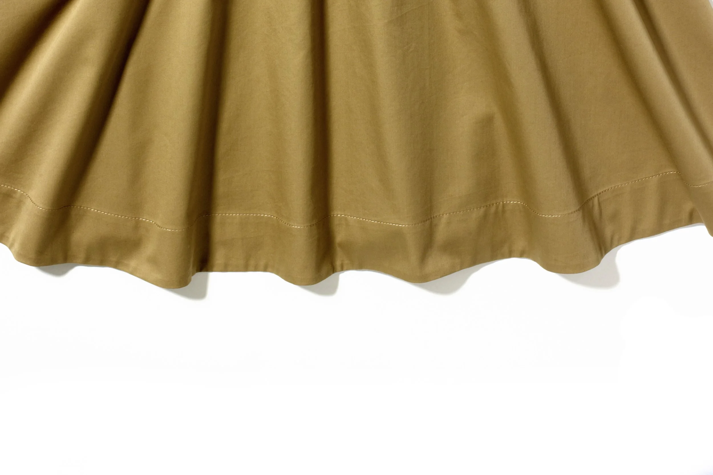 Beige or tan skirt with pleats, hanging against a white background.