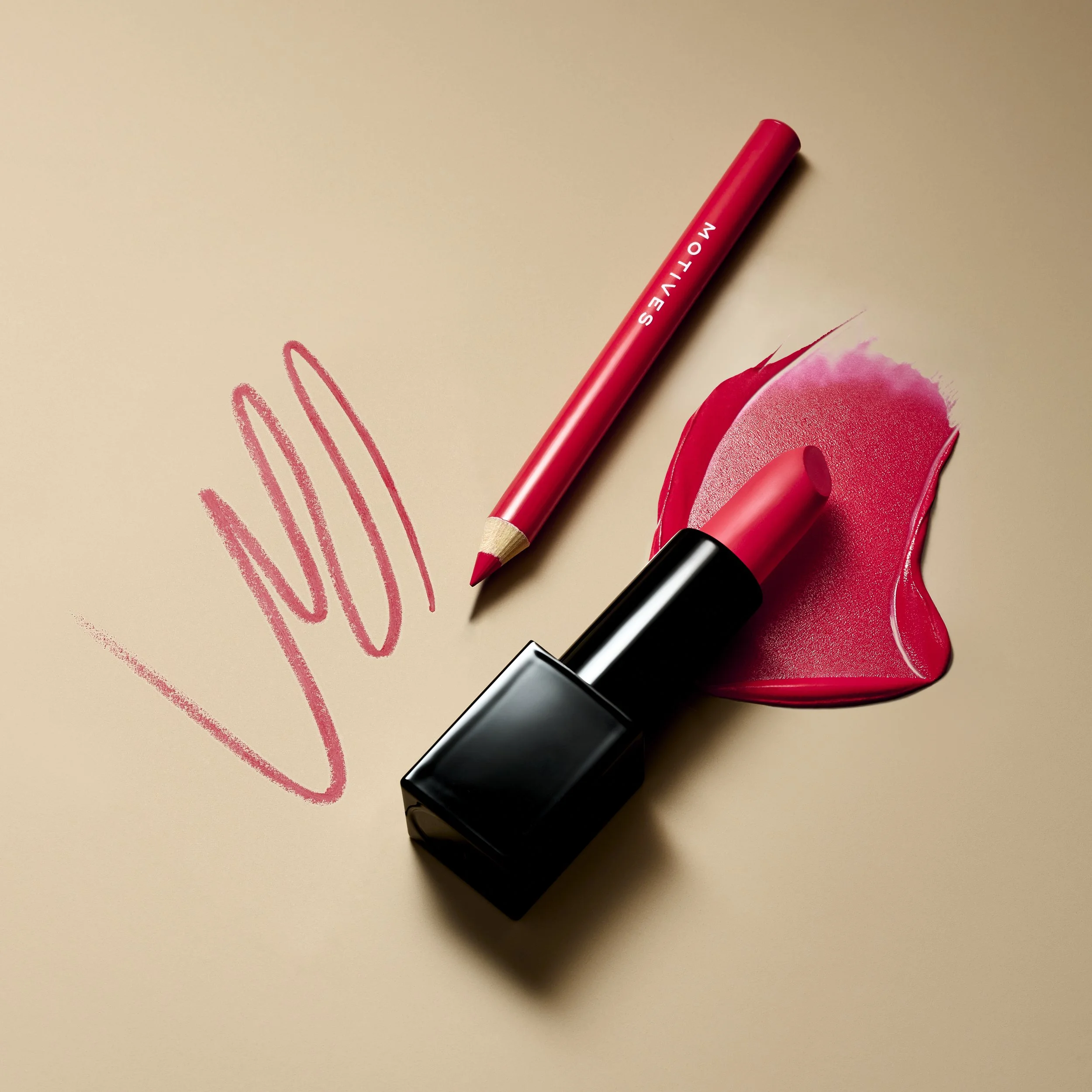 A red lipstick, a red lip liner, and a pink lipstick smear with a makeup swatch on a beige background.