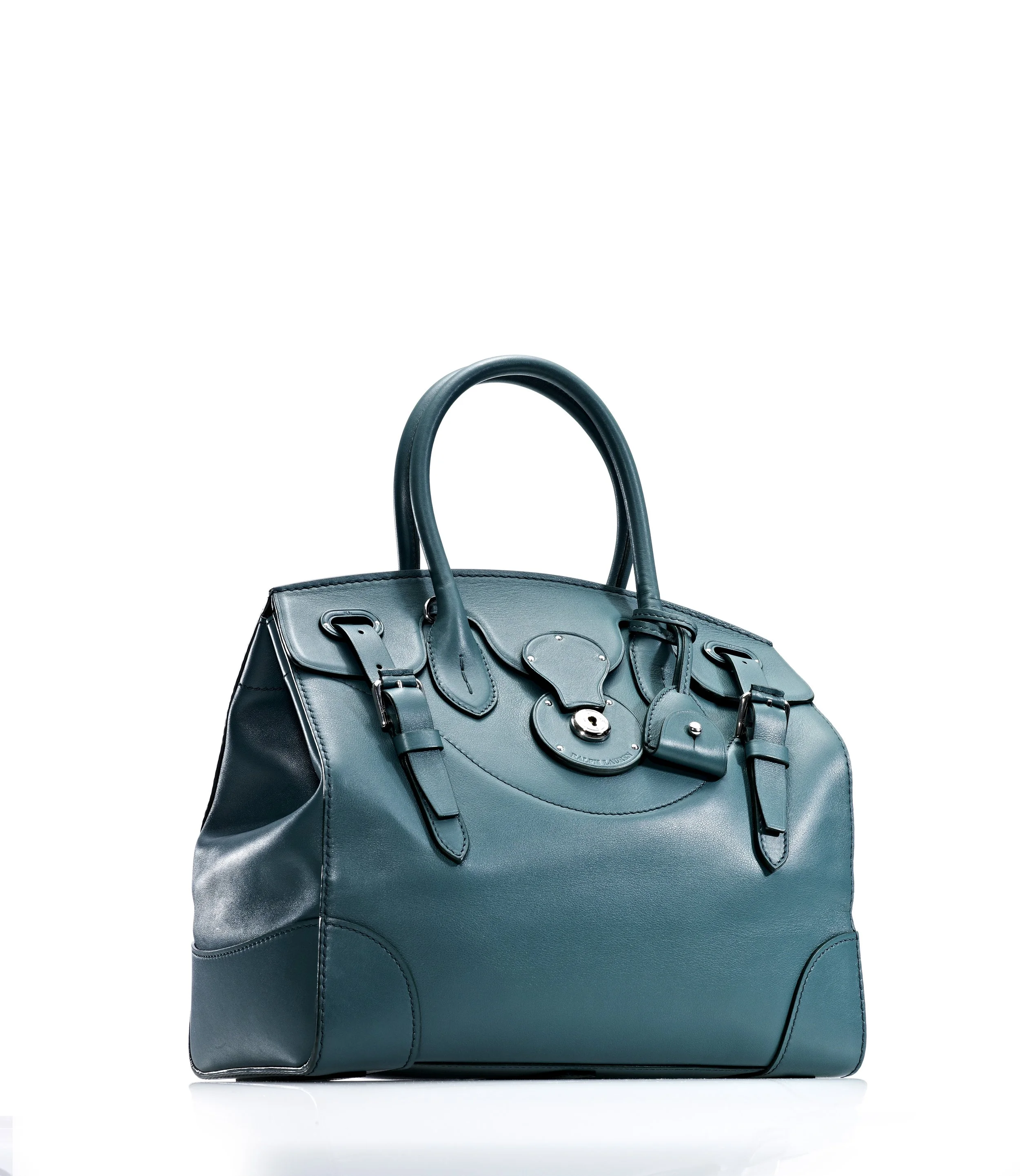 A teal leather designer handbag with buckles and a lock, set against a white background.