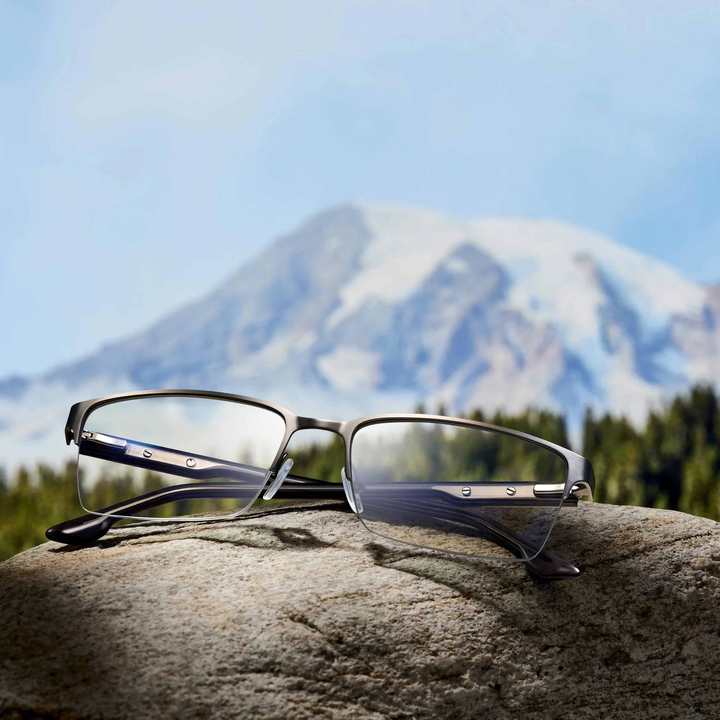 Eyeglasses resting on a rock with a snowy mountain in the background.