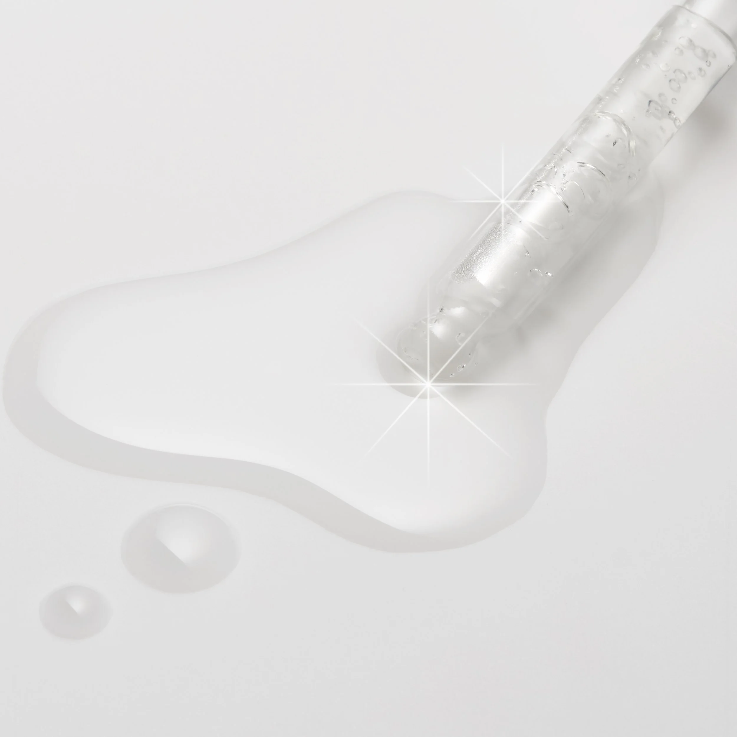A clear glass test tube spilling a liquid that looks like water onto a white surface, creating a small pool.