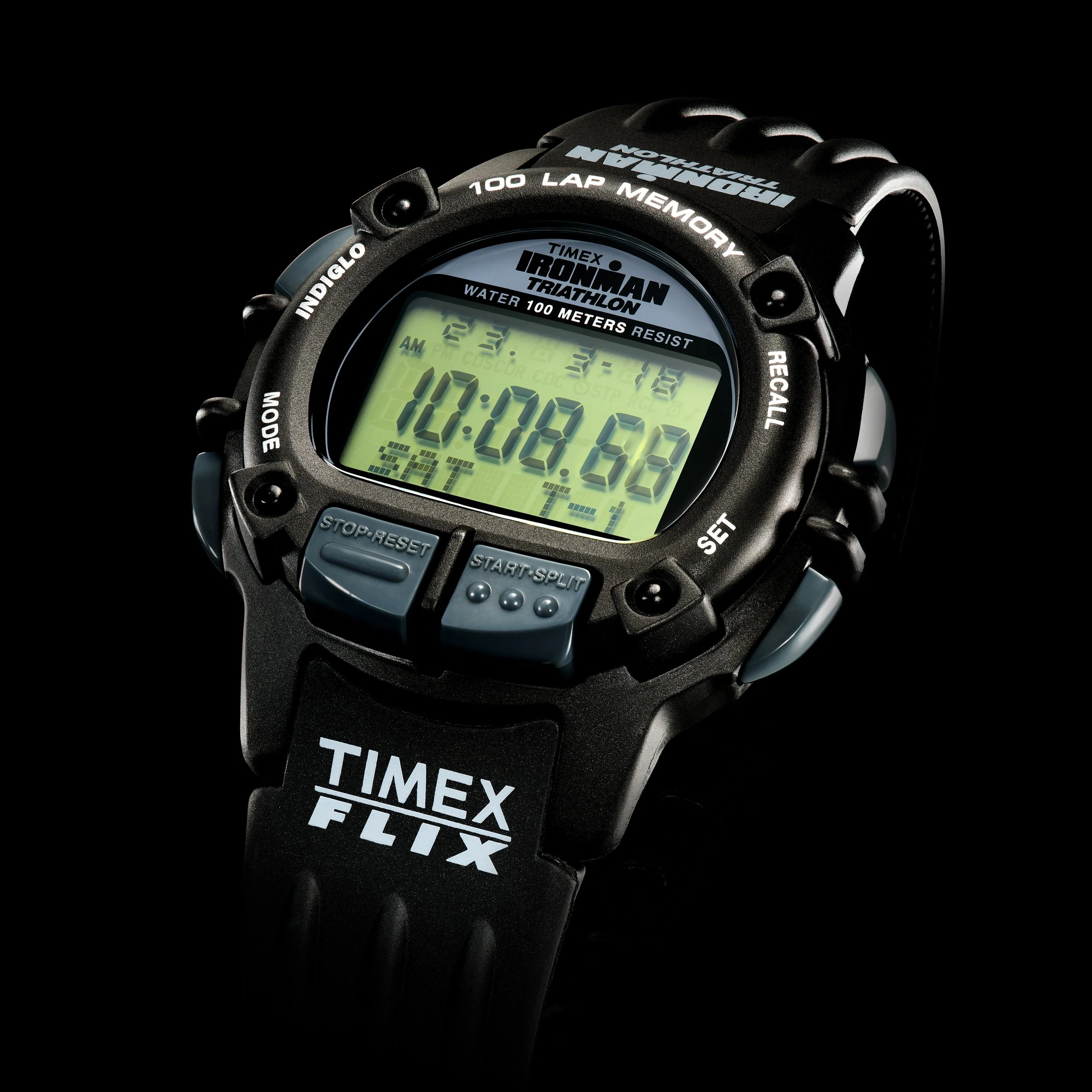 Close-up of a black Timex Ironman triathlon digital sports watch showing the time 10:08:58 on a green display, with various labels and buttons around the face, against a black background.