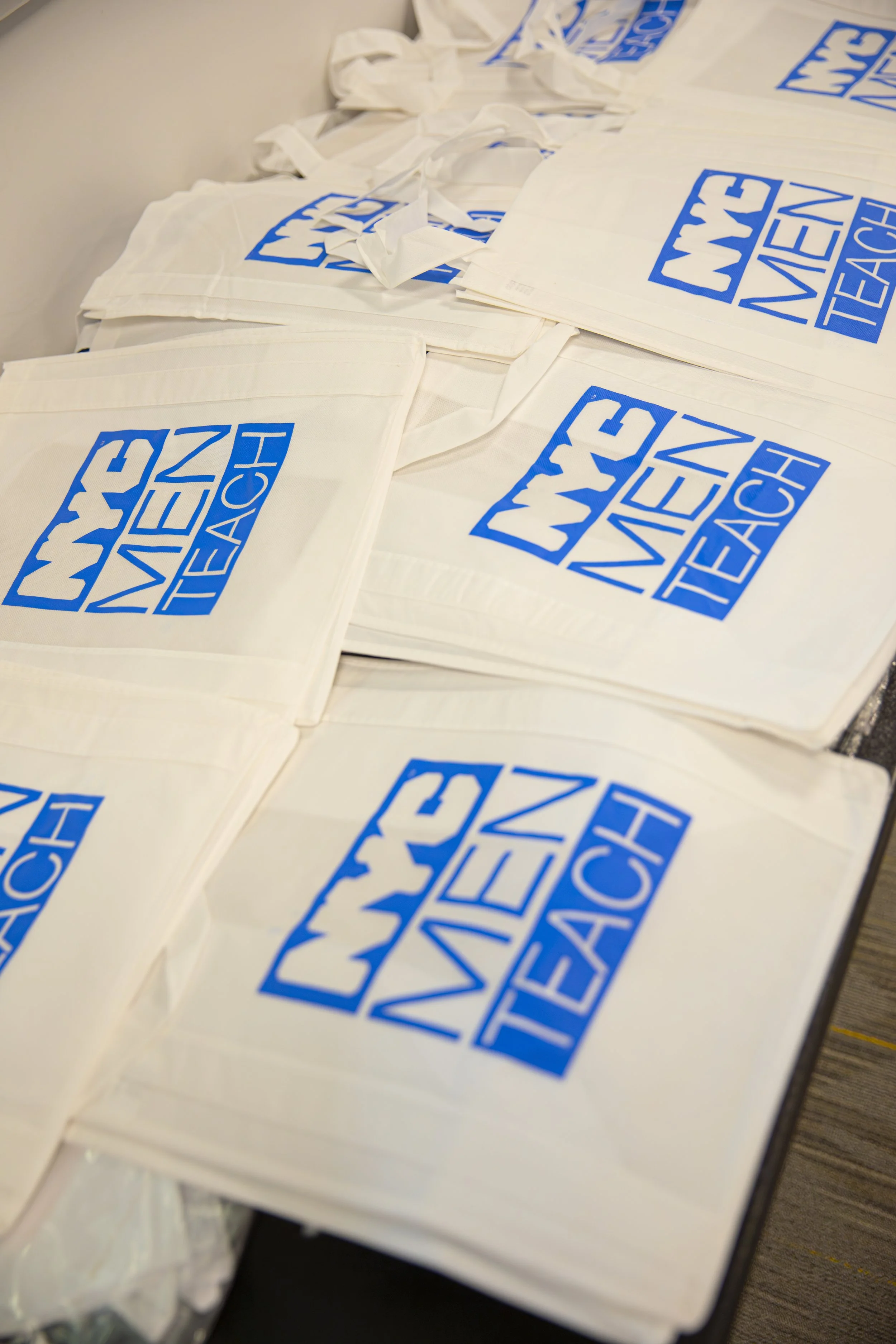 Multiple white tote bags with the blue and white 'WNY WAVE BEACH' logo printed on them, arranged on a table.