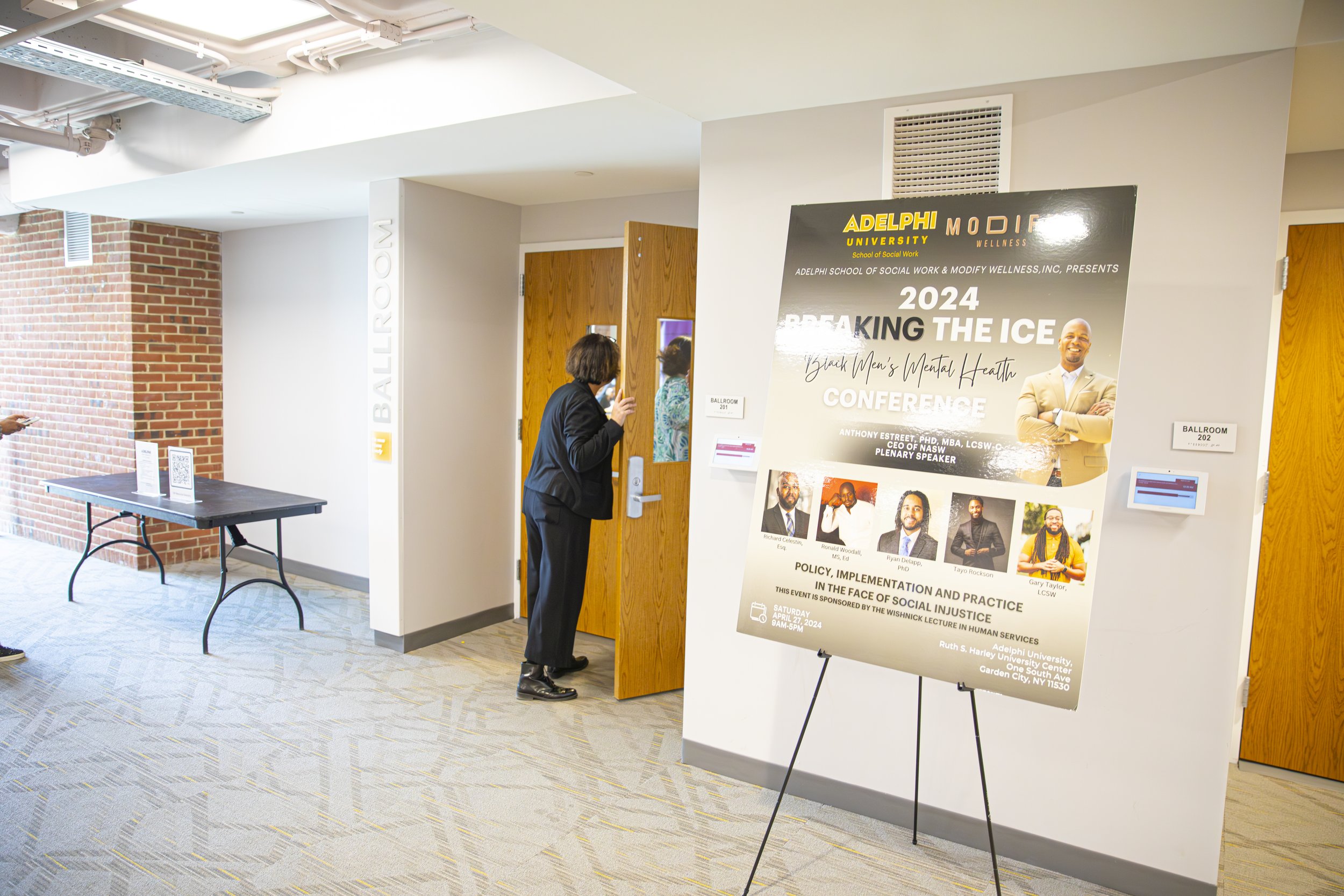 A conference poster titled 'Breaking the Ice,' featuring a smiling man in a beige suit with crossed arms. The event is at Adelphi University, School of Social Work, on April 27, 2024, focusing on mental health, social justice, and policy, with speake