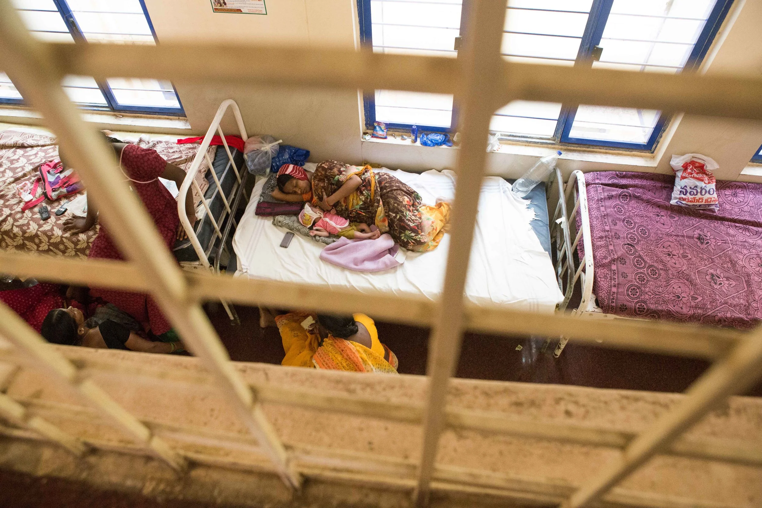 Sometimes there are not enough beds in the district hospital to accommodate the huge demand. The hospital graciously provides a temporary bed to a mother and a new born child in it’s corridor. Nalgonda District Hospital, Telangana