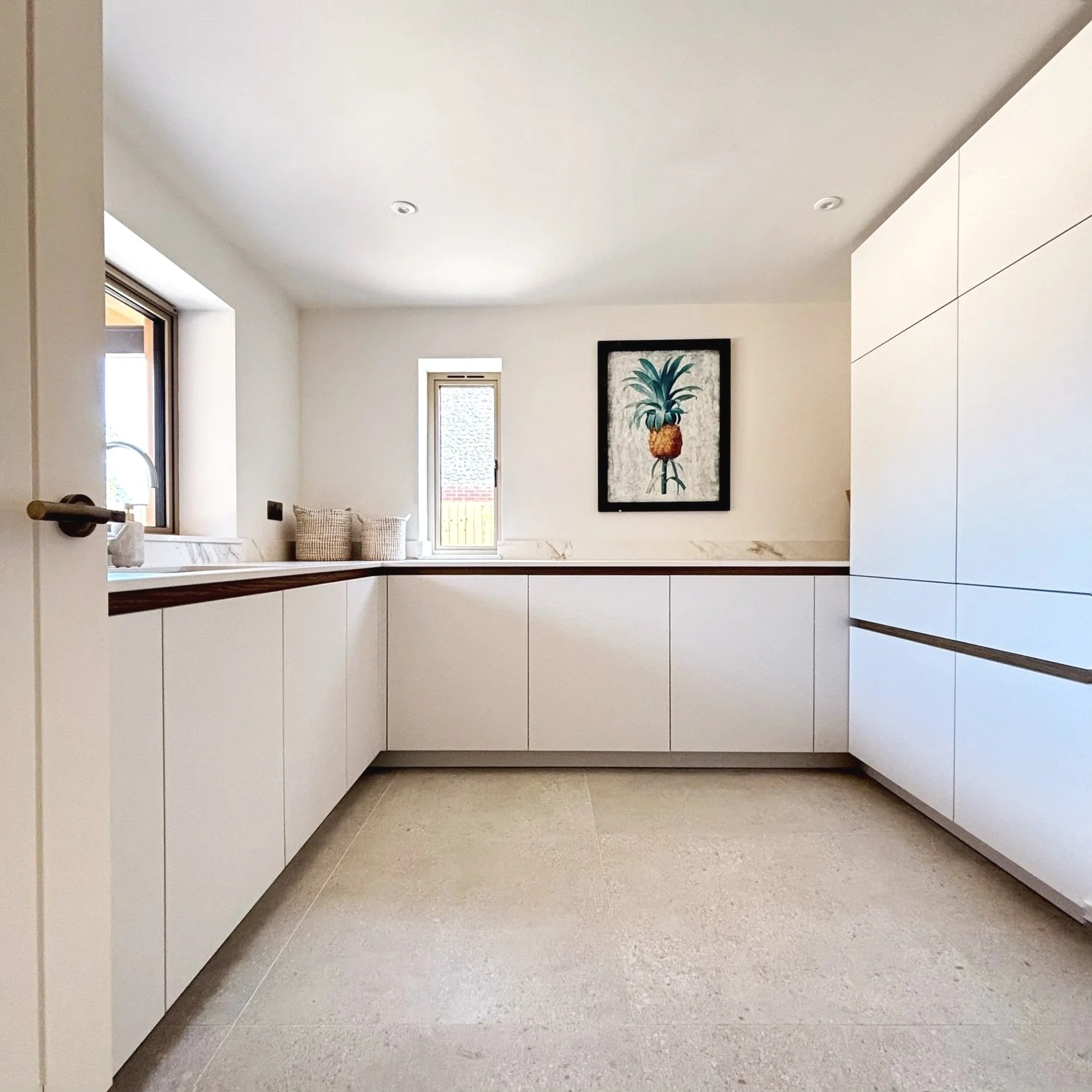 Modern utility with beach grey cabinets, ceramic countertops, and hidden laundry appliances.