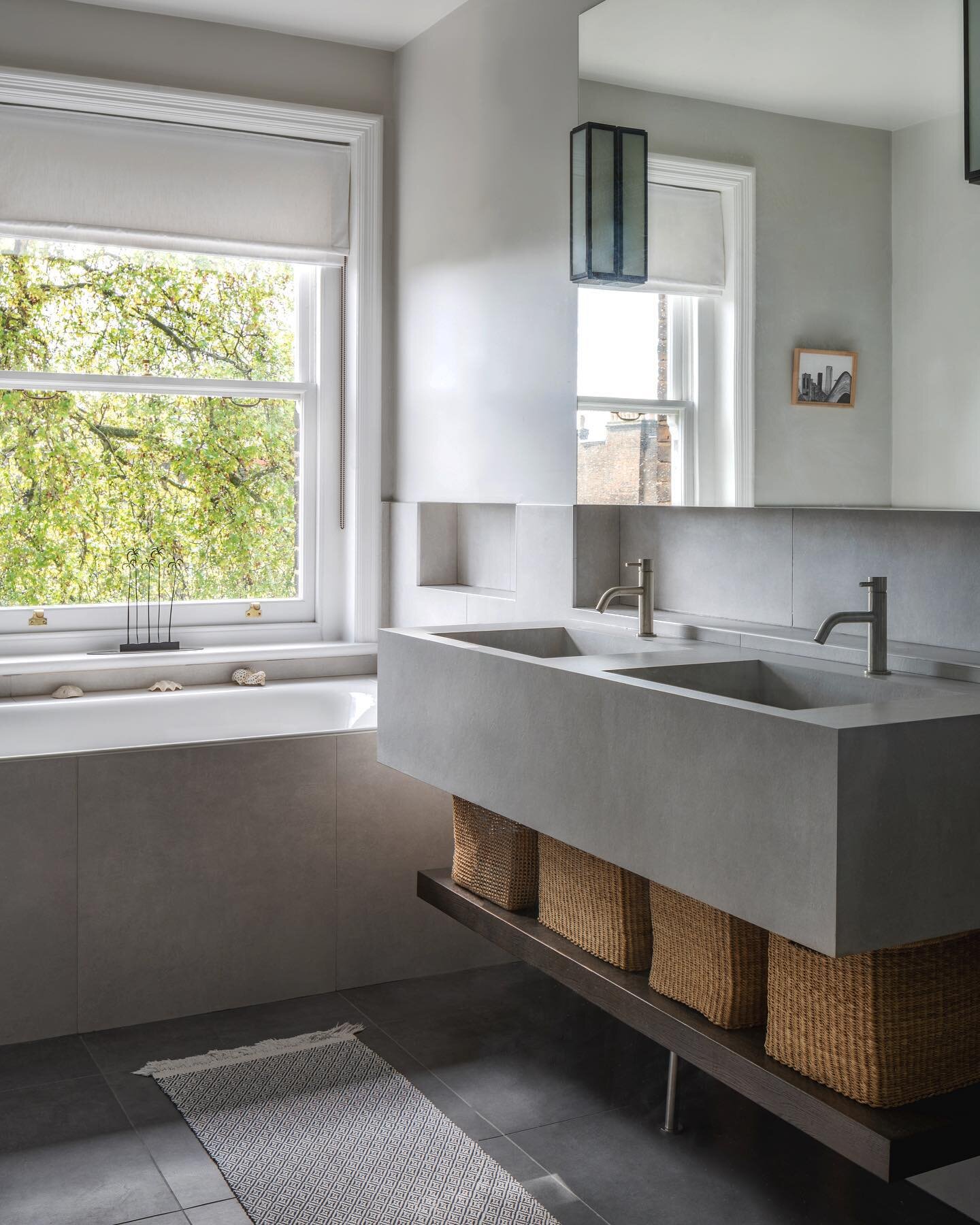 A jungle bath 🌳🥰

A concrete - esque bathroom with the perfect view. Bespoke porcelain grey double sink, warmed up with wicker baskets and a beautiful view while chilling out 🛀 

Photo by @vigojansons 

#interiordesign #design #refurbishment #refu
