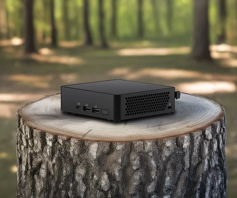 ASUS NUC placed on a wooden surface with a monitor behind it